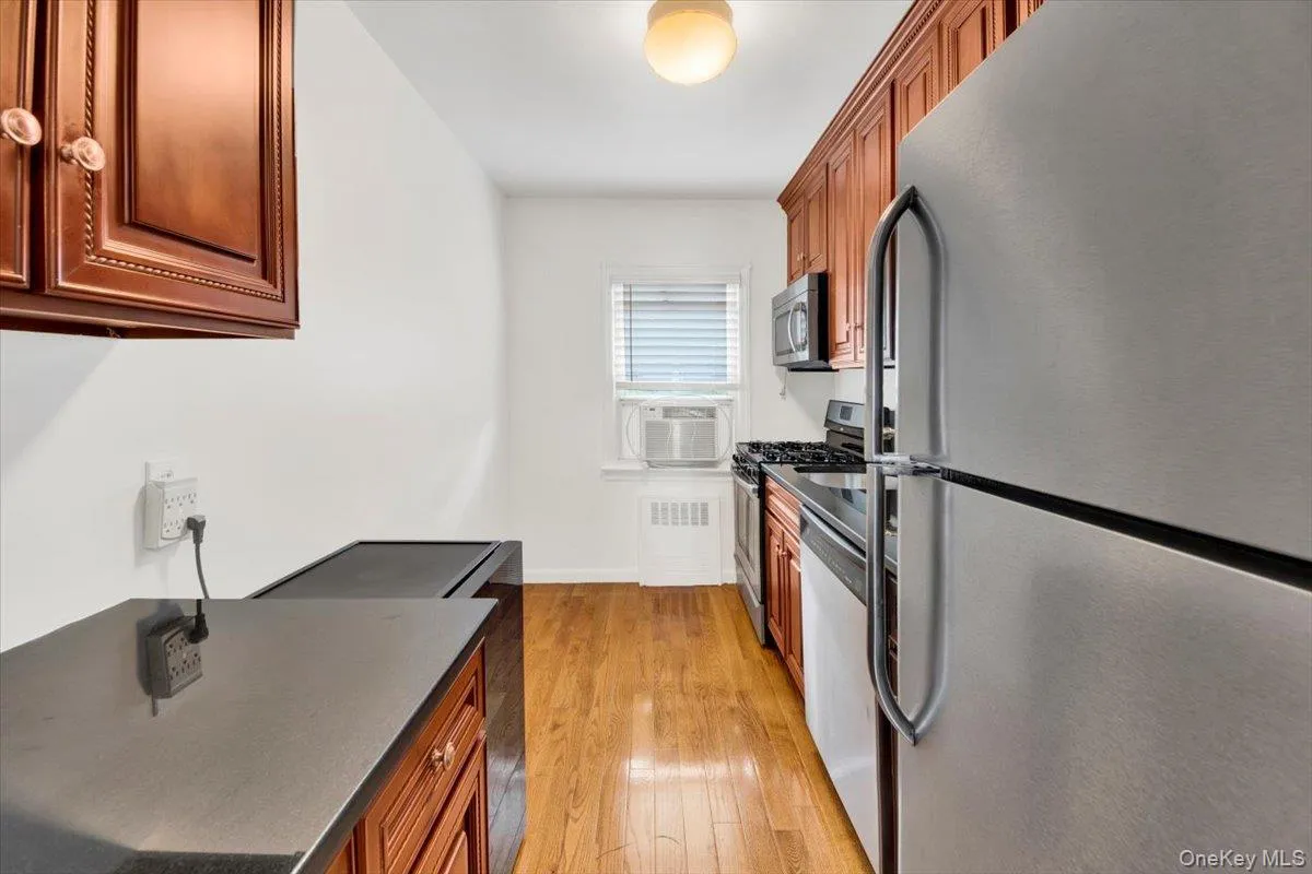 Kitchen with stainless steel appliances, dark stone countertops, light wood-style floors & cabinets Kitchen with stainless steel appliances, dark stone countertops, light wood-style floors & cabinets