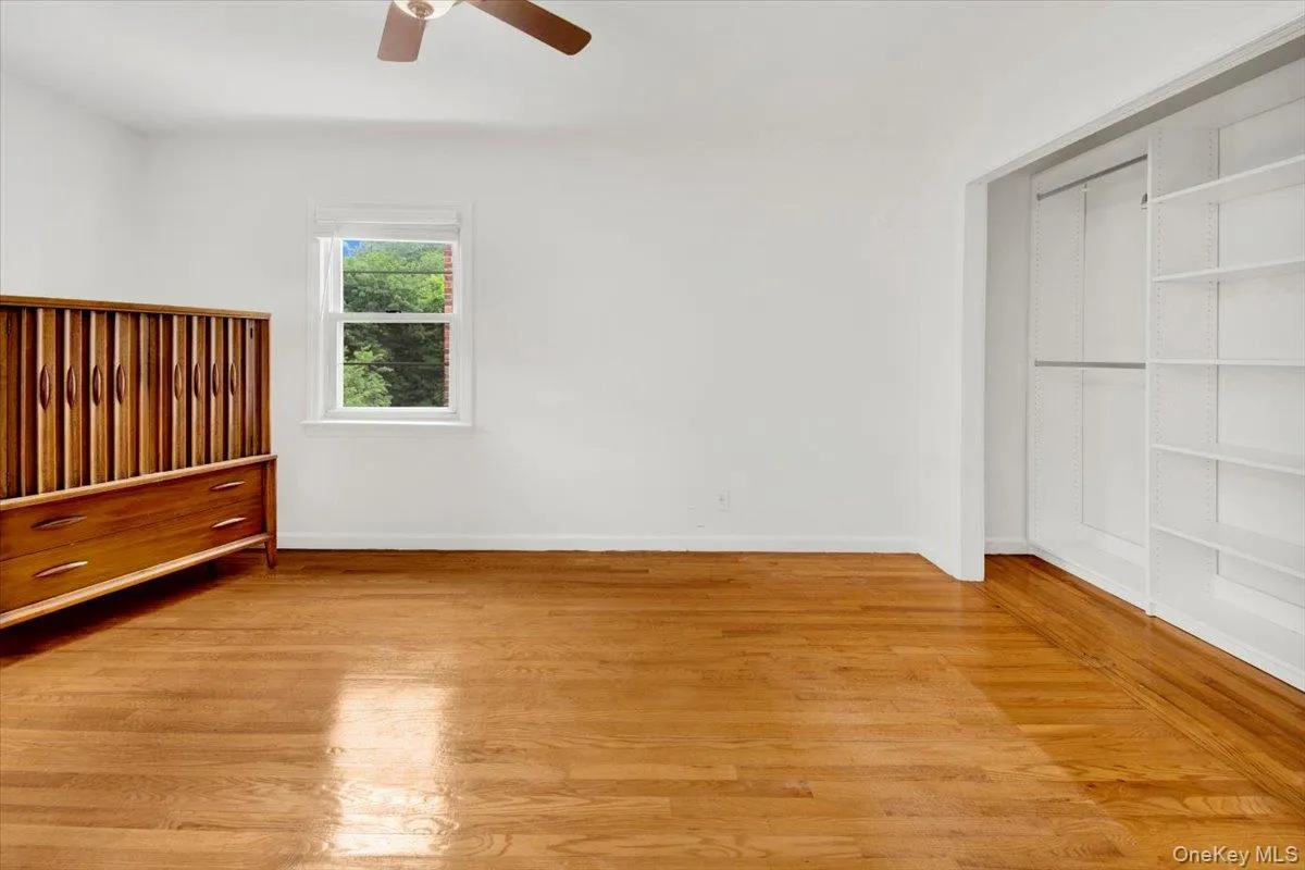 Unfurnished bedroom with light wood flooring, ceiling fan and spacious closet Unfurnished bedroom with light wood flooring, ceiling fan and spacious closet