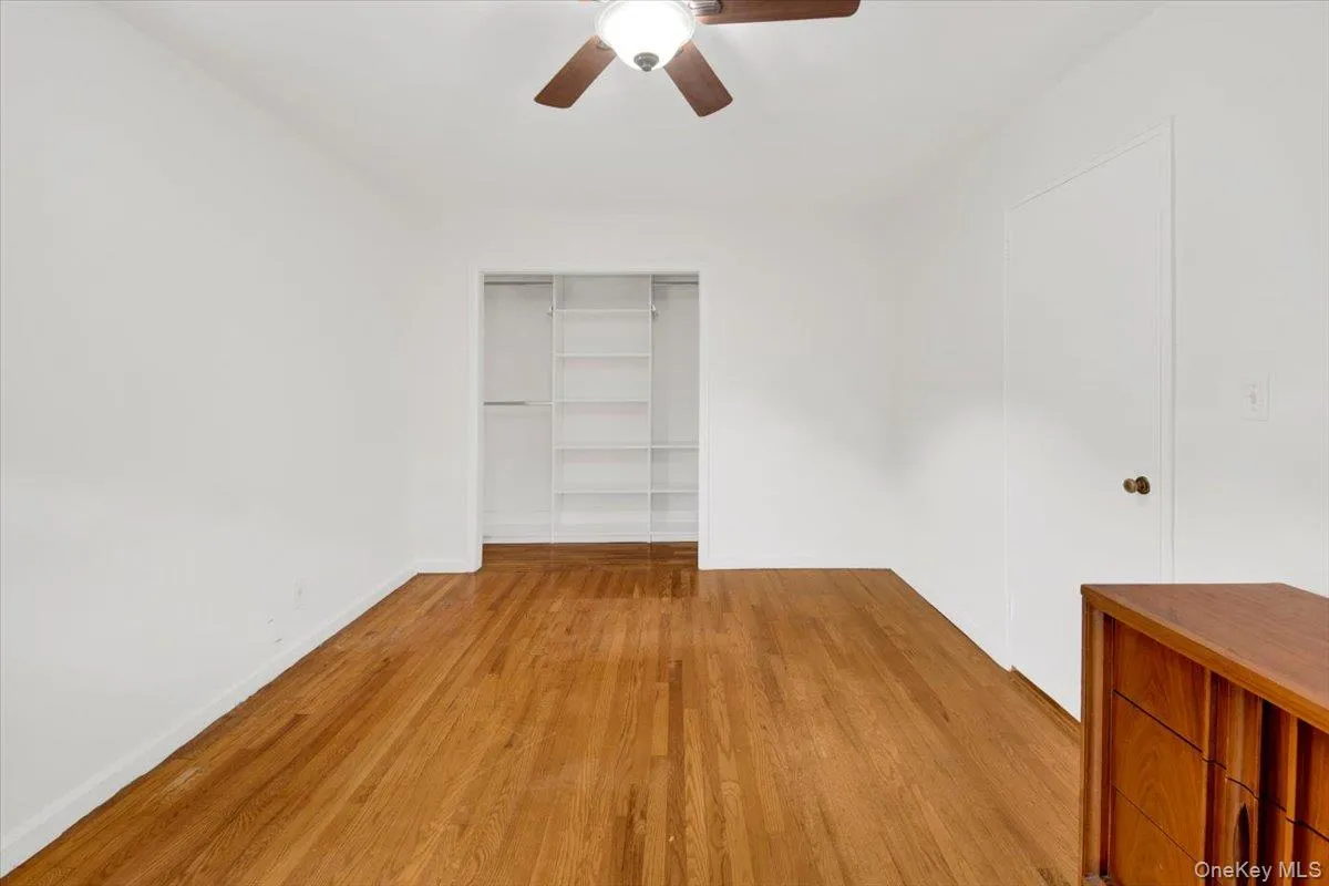 Unfurnished bedroom with light wood flooring, ceiling fan and spacious closet Unfurnished bedroom with light wood flooring, ceiling fan and spacious closet