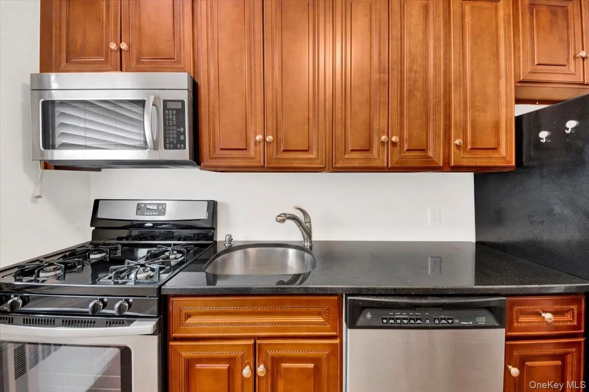 Kitchen with stainless steel appliances, dark stone countertops, light wood-style floors & cabinets Kitchen with stainless steel appliances, dark stone countertops, light wood-style floors & cabinets