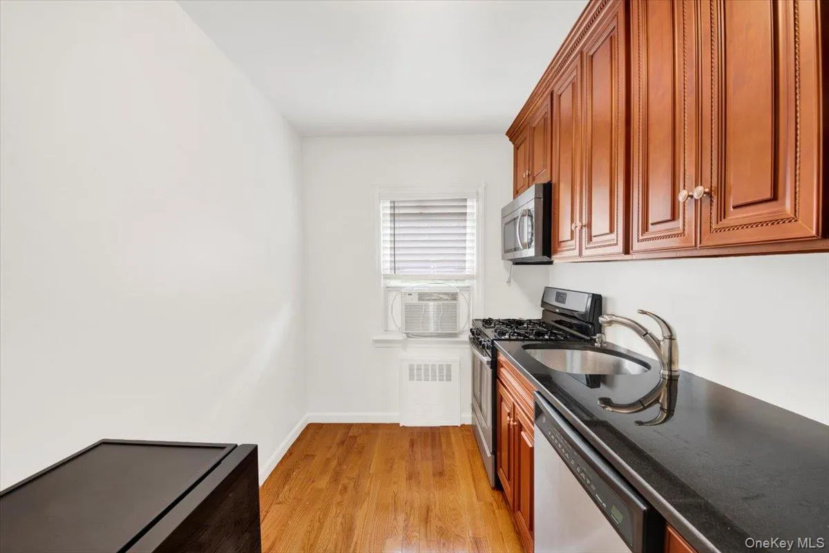 Kitchen with stainless steel appliances, dark stone countertops, light wood-style floors & cabinets Kitchen with stainless steel appliances, dark stone countertops, light wood-style floors & cabinets