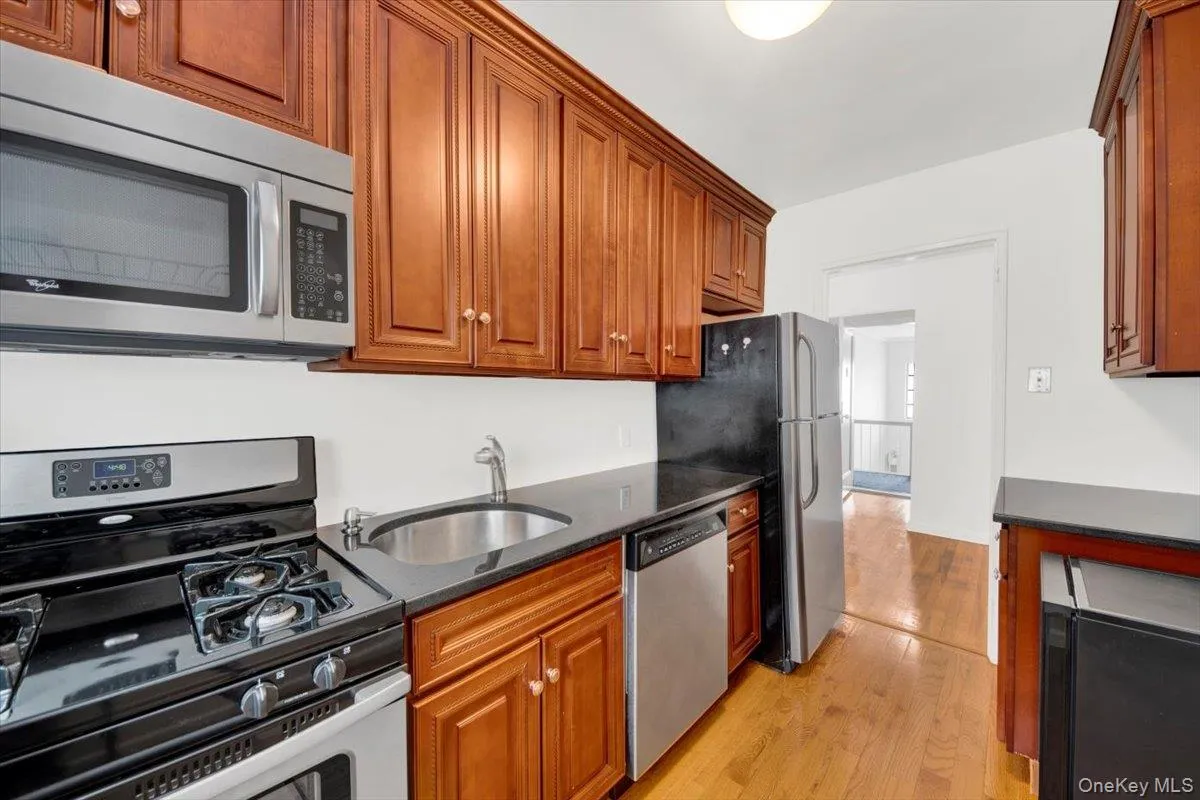 Kitchen with stainless steel appliances, dark stone countertops, light wood-style floors & cabinets Kitchen with stainless steel appliances, dark stone countertops, light wood-style floors & cabinets