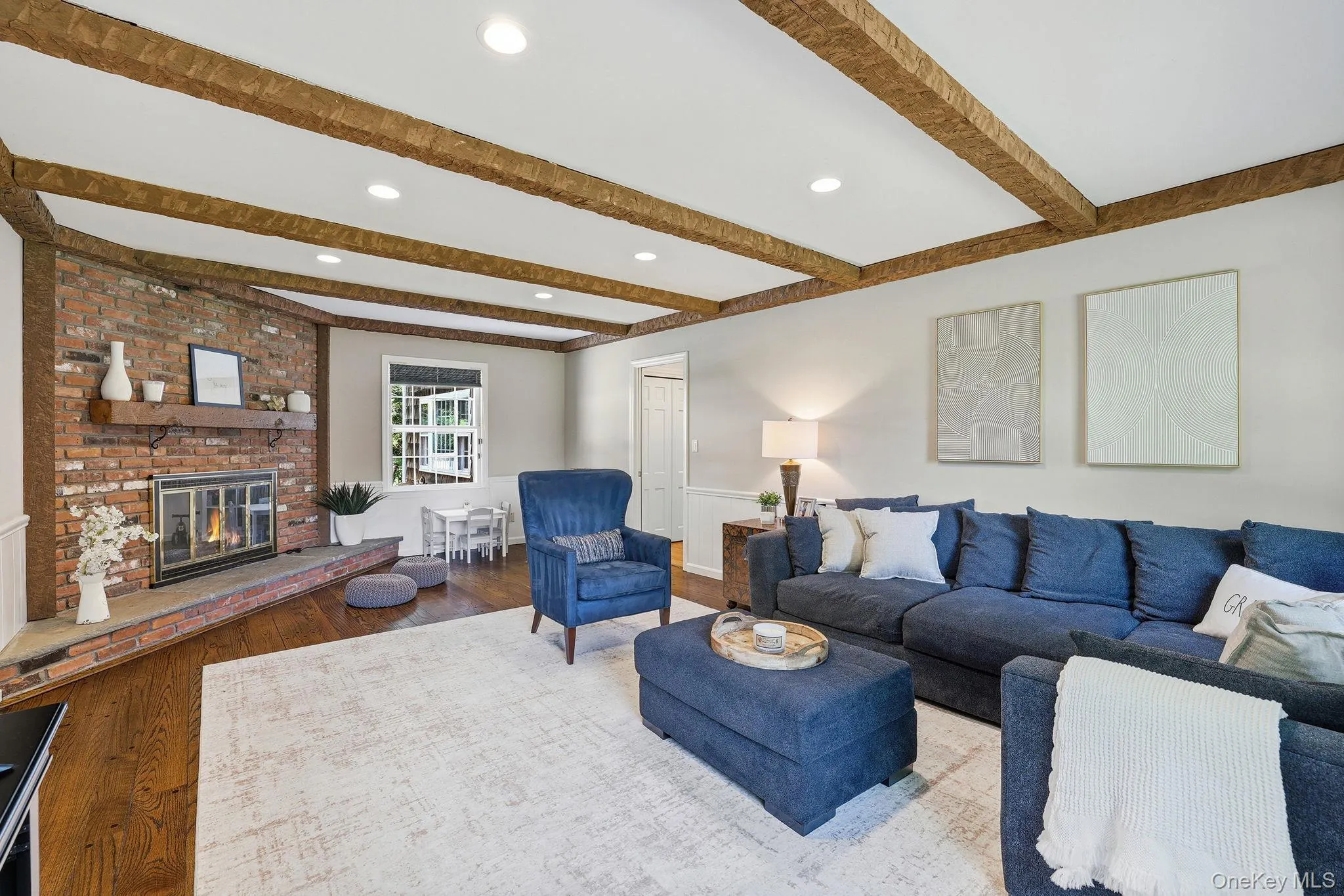 Great room conveniently located just off the kitchen featuring gleaming hardwood floors, beamed ceilings and a wood-burning fireplace Great room conveniently located just off the kitchen featuring gleaming hardwood floors, beamed ceilings and a wood-burning fireplace