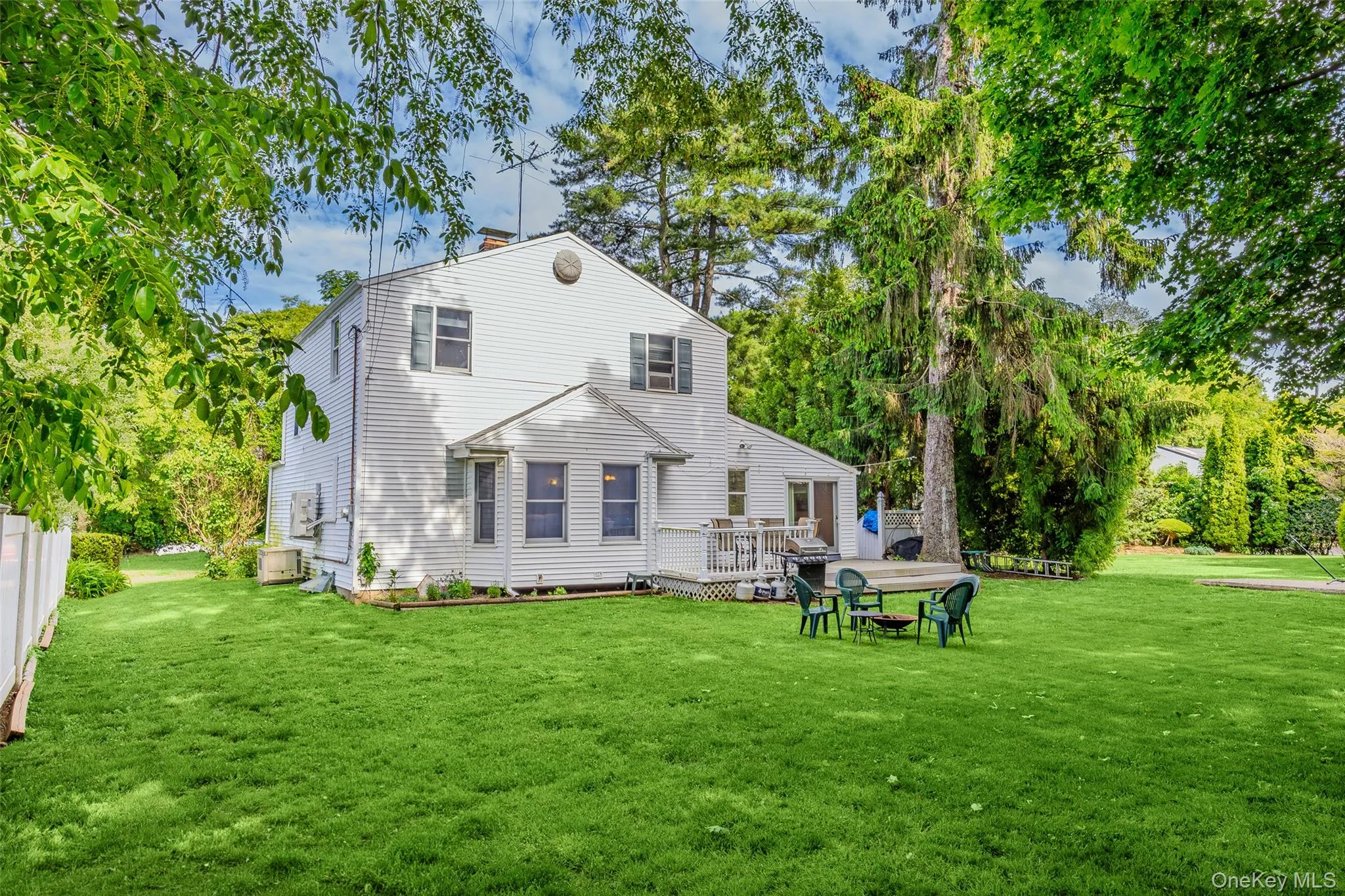 Expansive rear yard featuring a large wooden deck and a mature tree canopy Expansive rear yard featuring a large wooden deck and a mature tree canopy