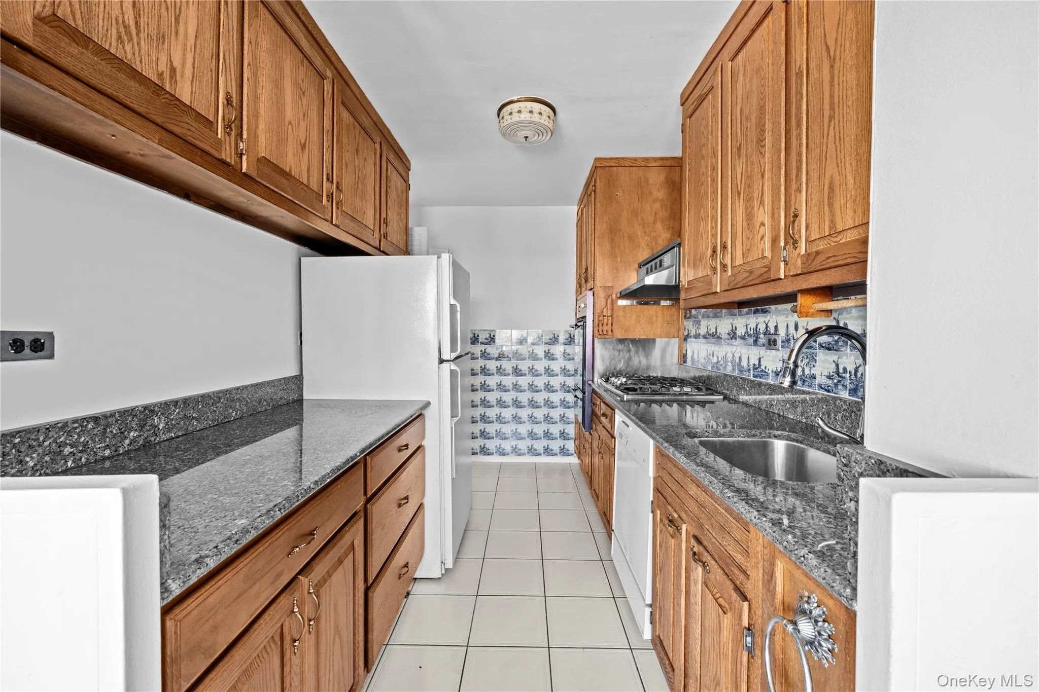 Walk through kitchen with wooden cabinets and charming detailed tiles Walk through kitchen with wooden cabinets and charming detailed tiles