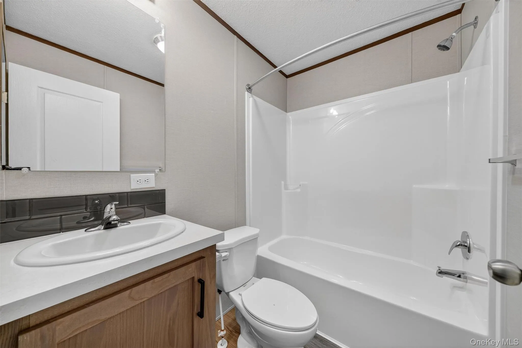 Bathroom with bathing tub / shower combination, ornamental molding, vanity, and a textured ceiling Bathroom with bathing tub / shower combination, ornamental molding, vanity, and a textured ceiling