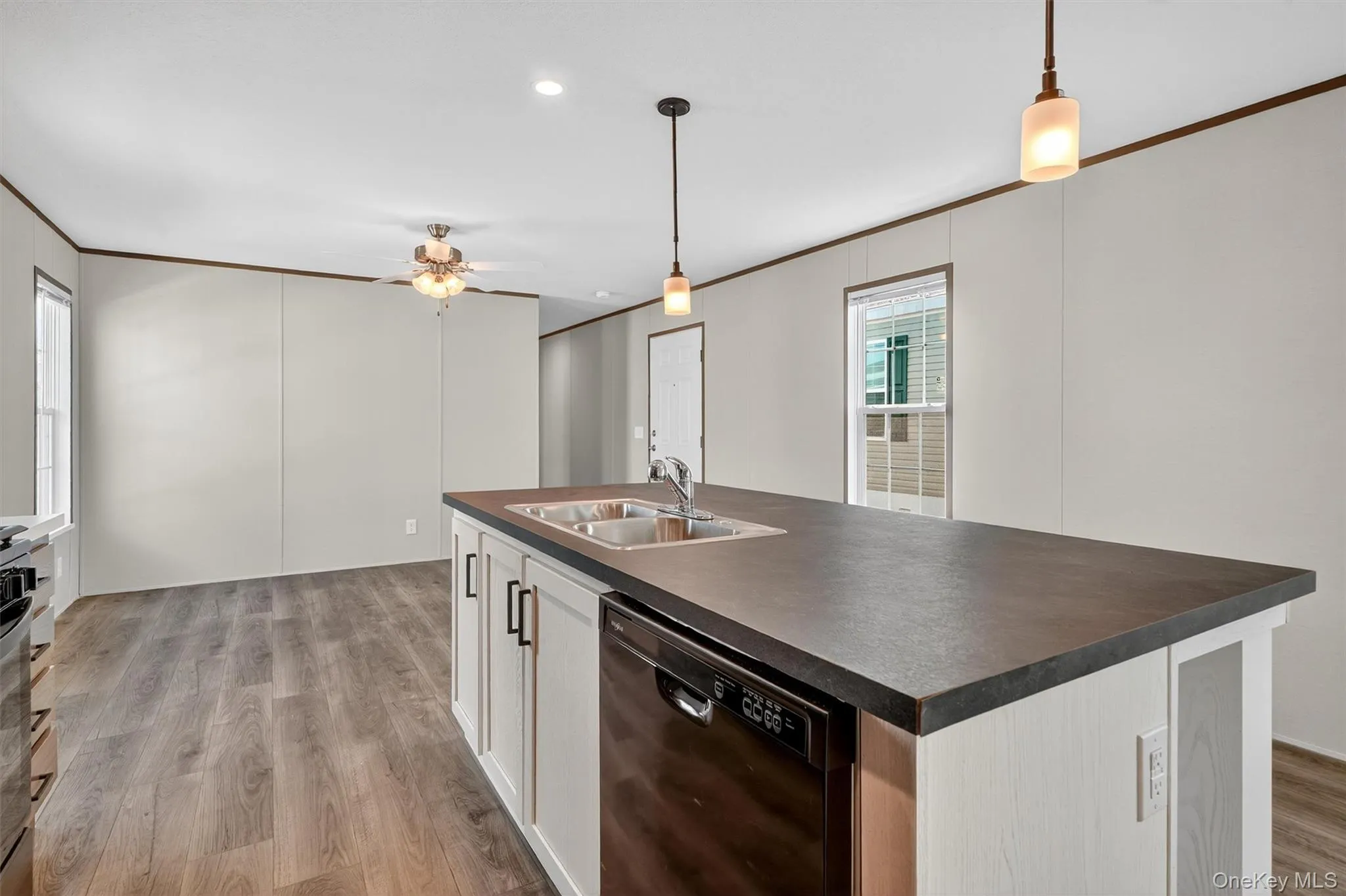 Kitchen with crown molding, a center island with sink, black dishwasher, pendant lighting, and dark countertops Kitchen with crown molding, a center island with sink, black dishwasher, pendant lighting, and dark countertops