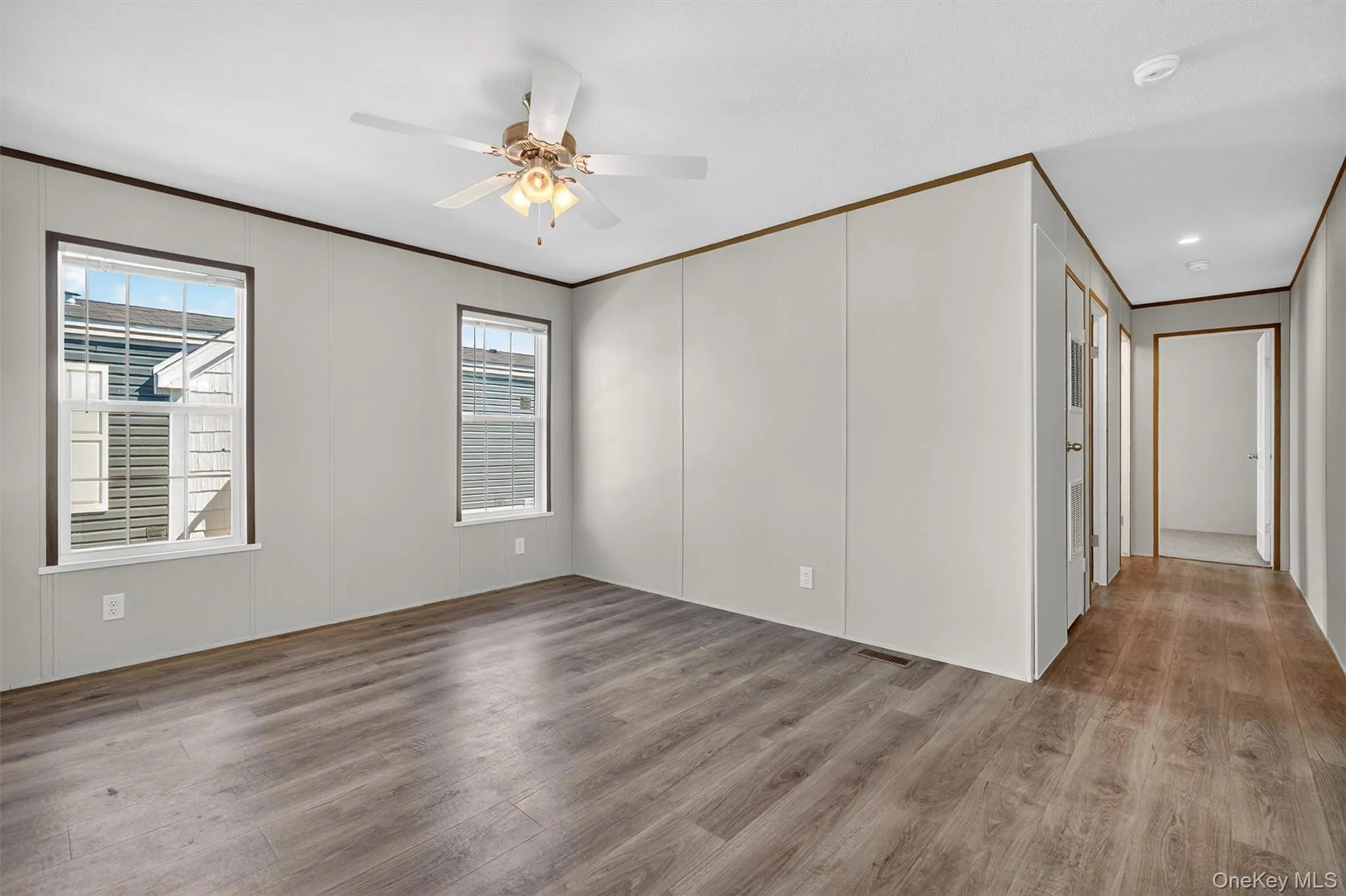 Unfurnished room with ornamental molding, wood finished floors, and a ceiling fan Unfurnished room with ornamental molding, wood finished floors, and a ceiling fan