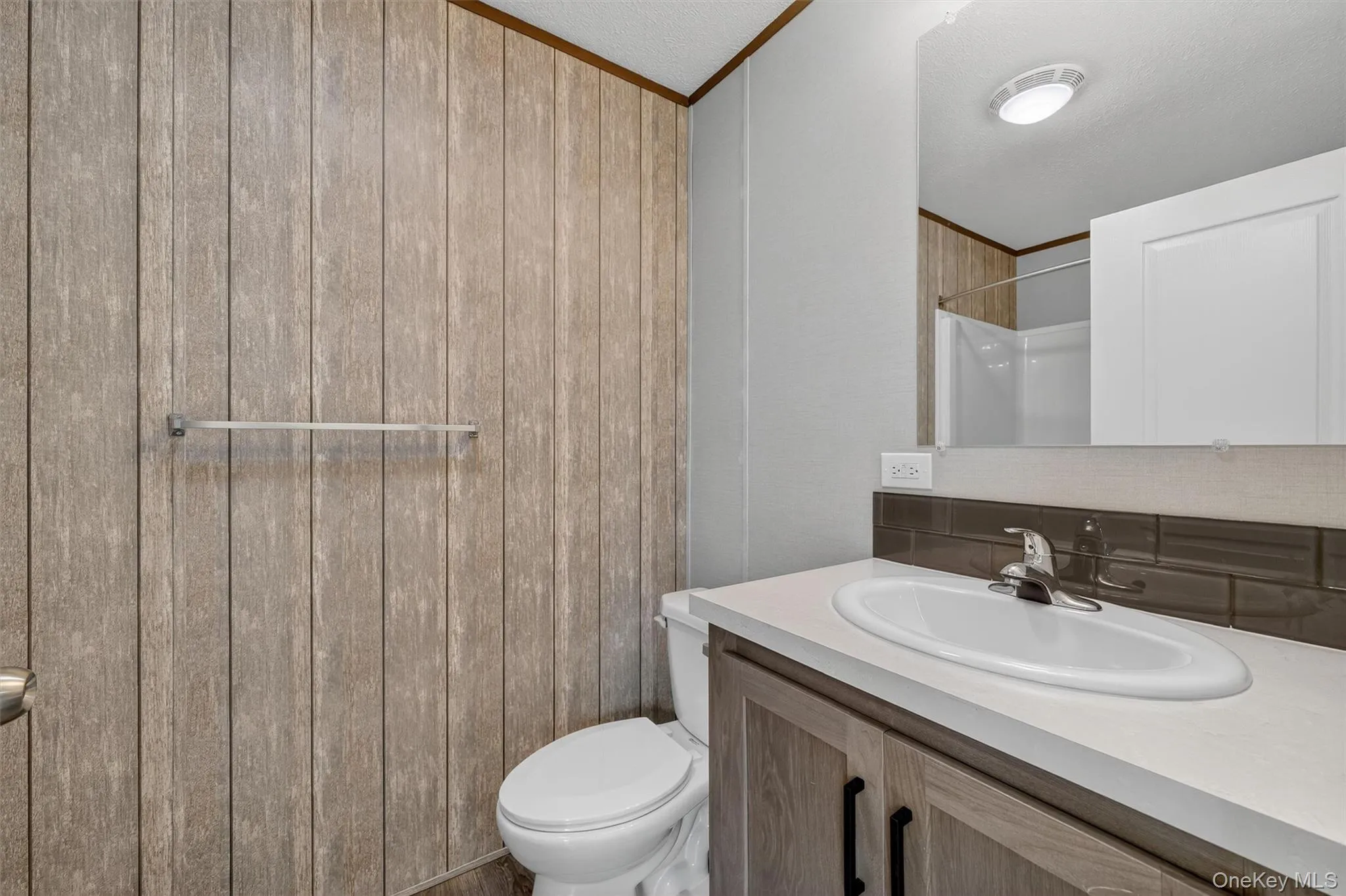 Full bathroom featuring vanity, ornamental molding, tasteful backsplash, and a shower Full bathroom featuring vanity, ornamental molding, tasteful backsplash, and a shower