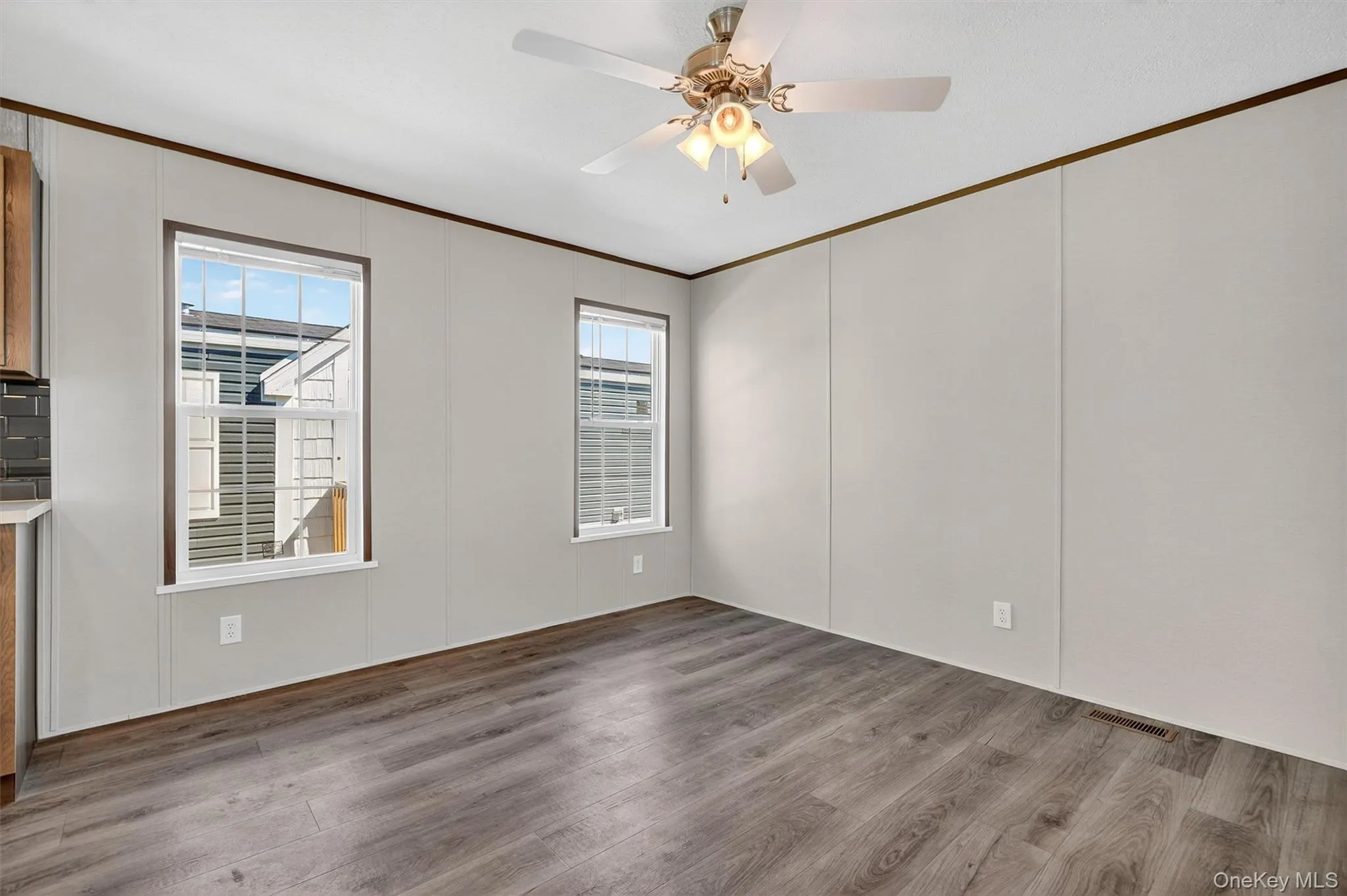 Empty room with ornamental molding, wood finished floors, ceiling fan, and a decorative wall Empty room with ornamental molding, wood finished floors, ceiling fan, and a decorative wall