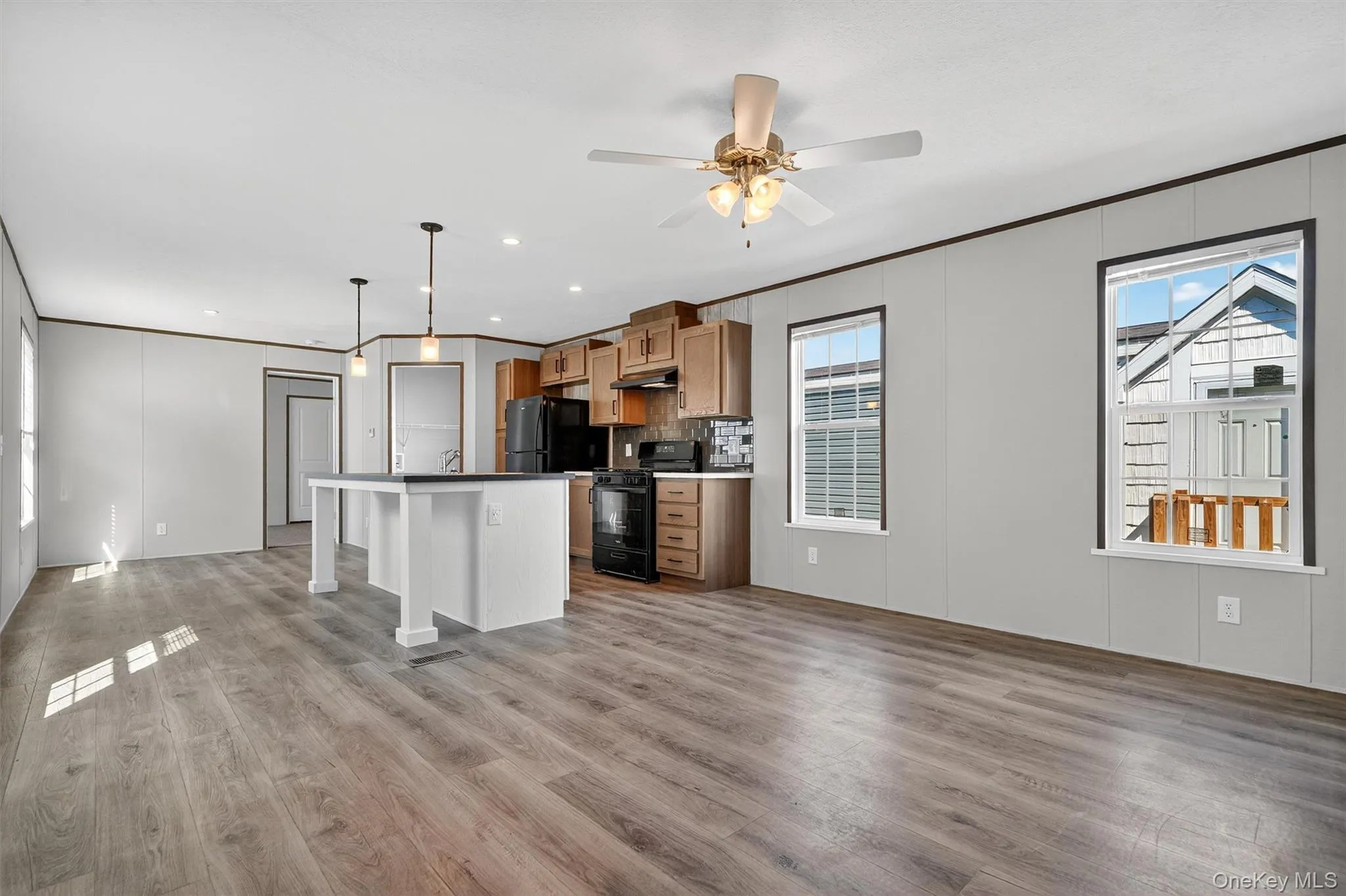 Kitchen featuring crown molding, a kitchen breakfast bar, black appliances, hanging light fixtures, and a center island Kitchen featuring crown molding, a kitchen breakfast bar, black appliances, hanging light fixtures, and a center island
