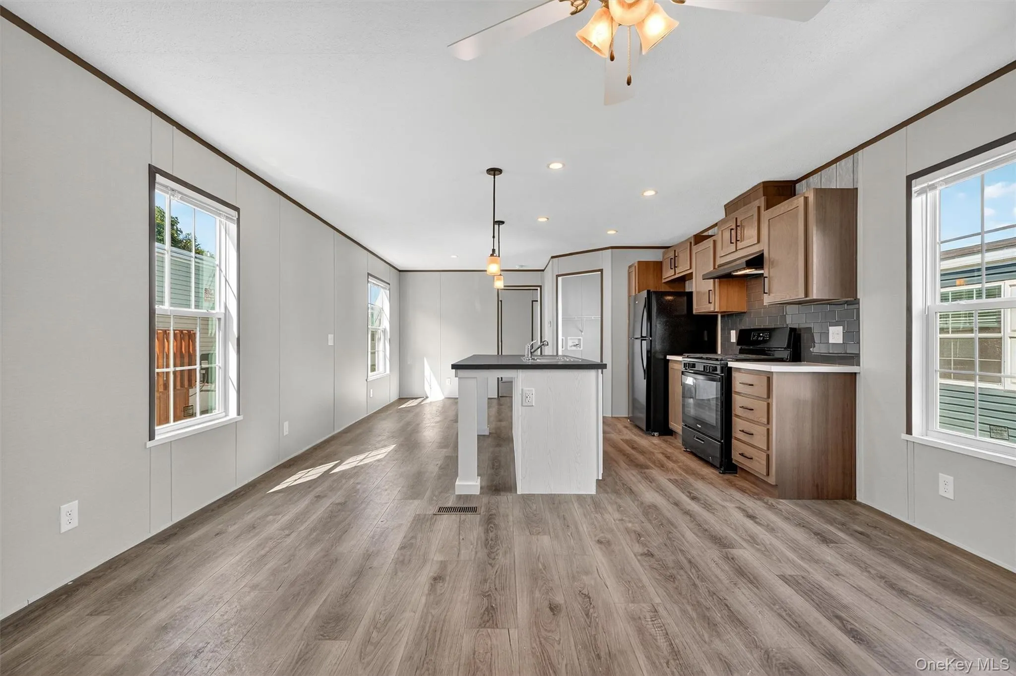 Kitchen with black gas stove, healthy amount of natural light, a kitchen island with sink, light wood-type flooring, and recessed lighting Kitchen with black gas stove, healthy amount of natural light, a kitchen island with sink, light wood-type flooring, and recessed lighting