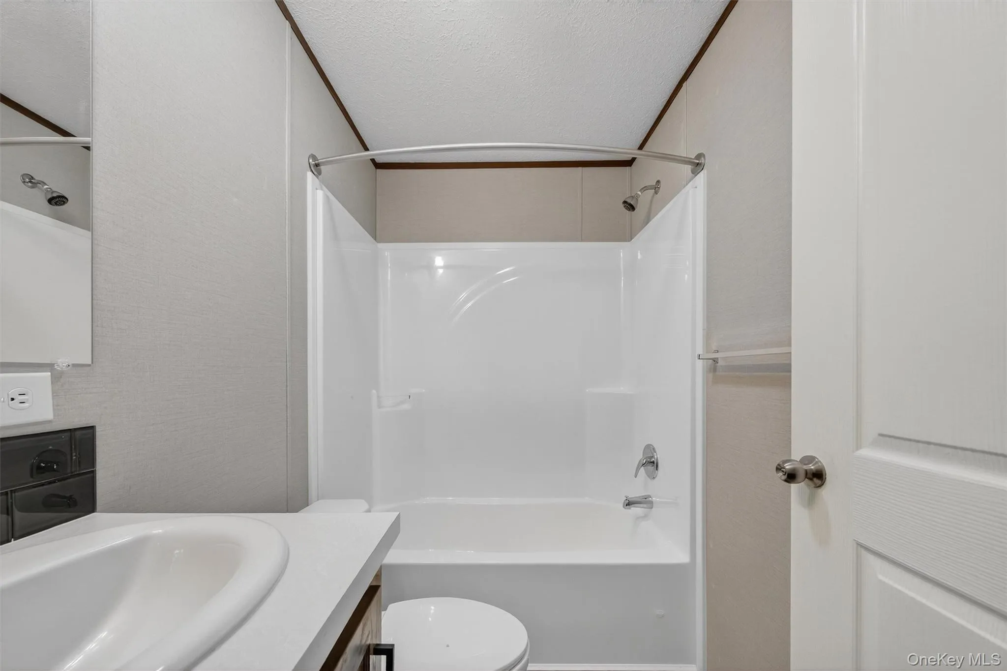 Bathroom with tub / shower combination, vanity, and a textured ceiling Bathroom with tub / shower combination, vanity, and a textured ceiling