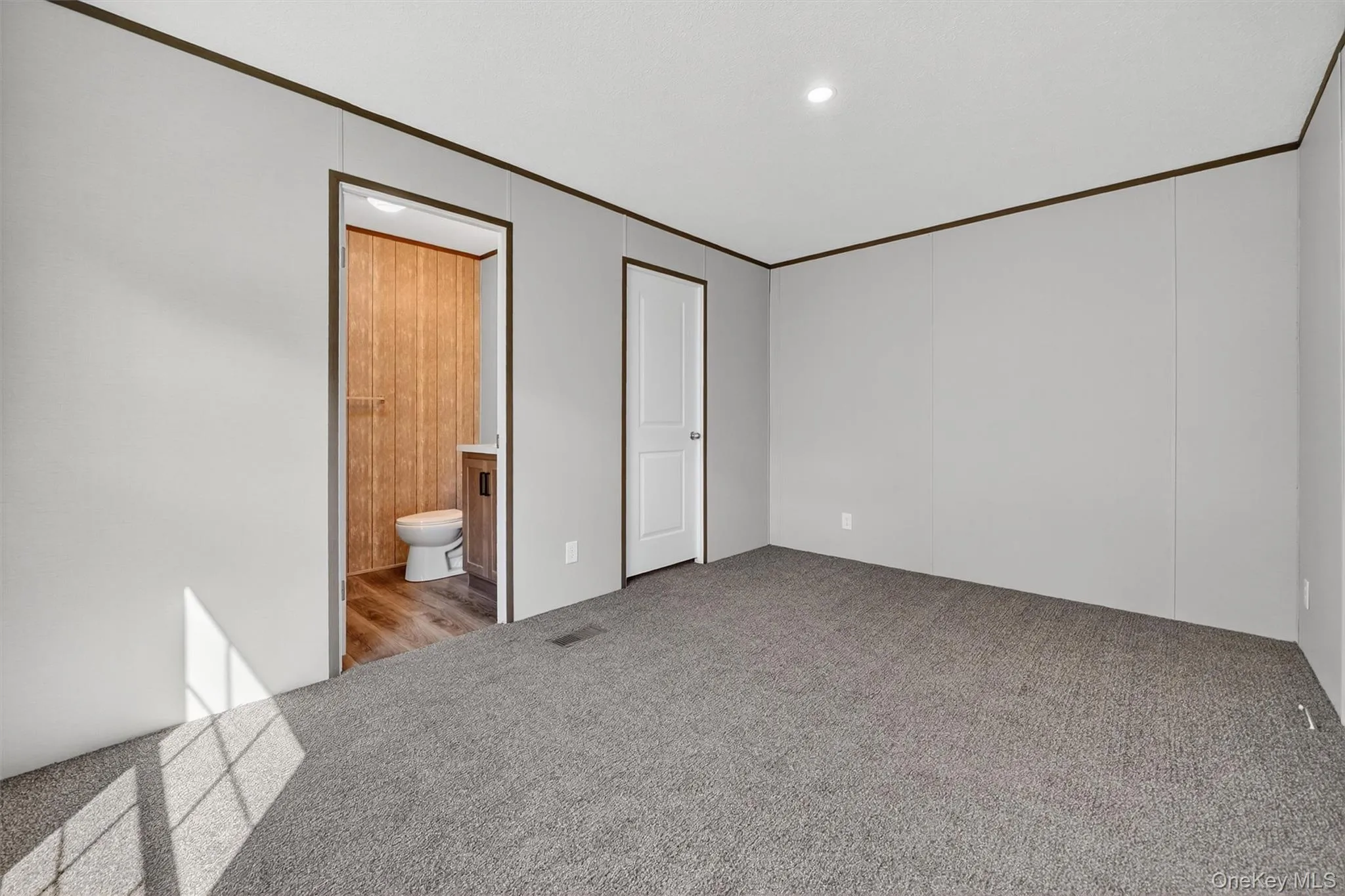 Unfurnished bedroom with carpet floors, ornamental molding, ensuite bathroom, and recessed lighting Unfurnished bedroom with carpet floors, ornamental molding, ensuite bathroom, and recessed lighting