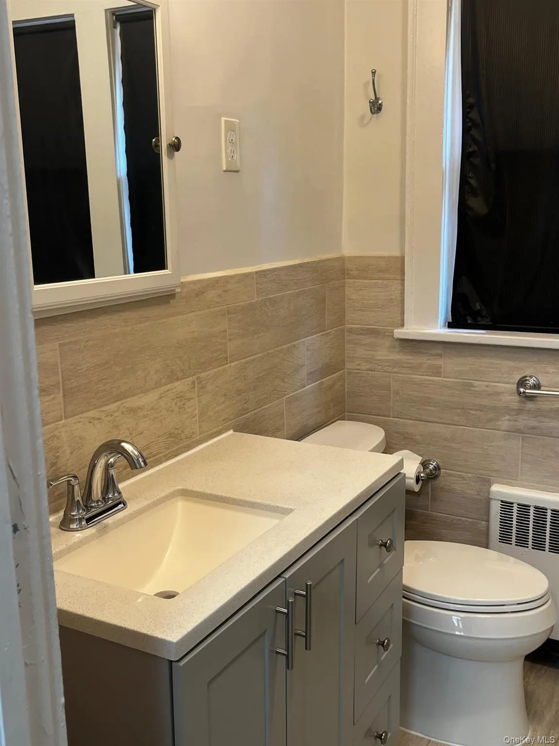 Bathroom featuring a gray vanity with integrated sink, chrome faucet, and coordinating cabinet hardware Bathroom featuring a gray vanity with integrated sink, chrome faucet, and coordinating cabinet hardware