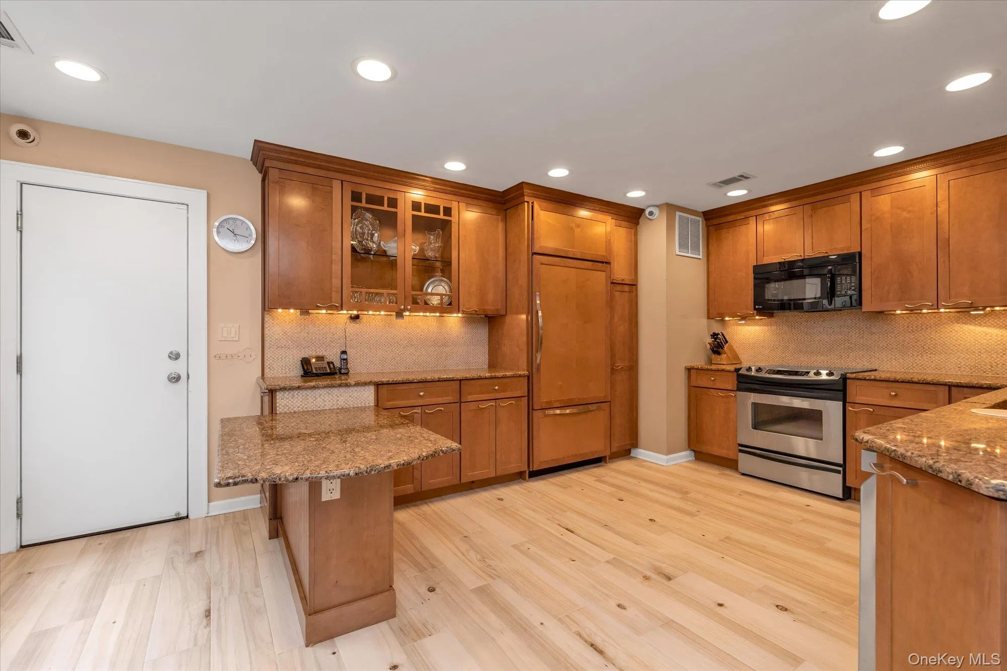 Kitchen featuring wood cabinetry, stainless steel appliances, granite countertops, and light tile flooring Kitchen featuring wood cabinetry, stainless steel appliances, granite countertops, and light tile flooring