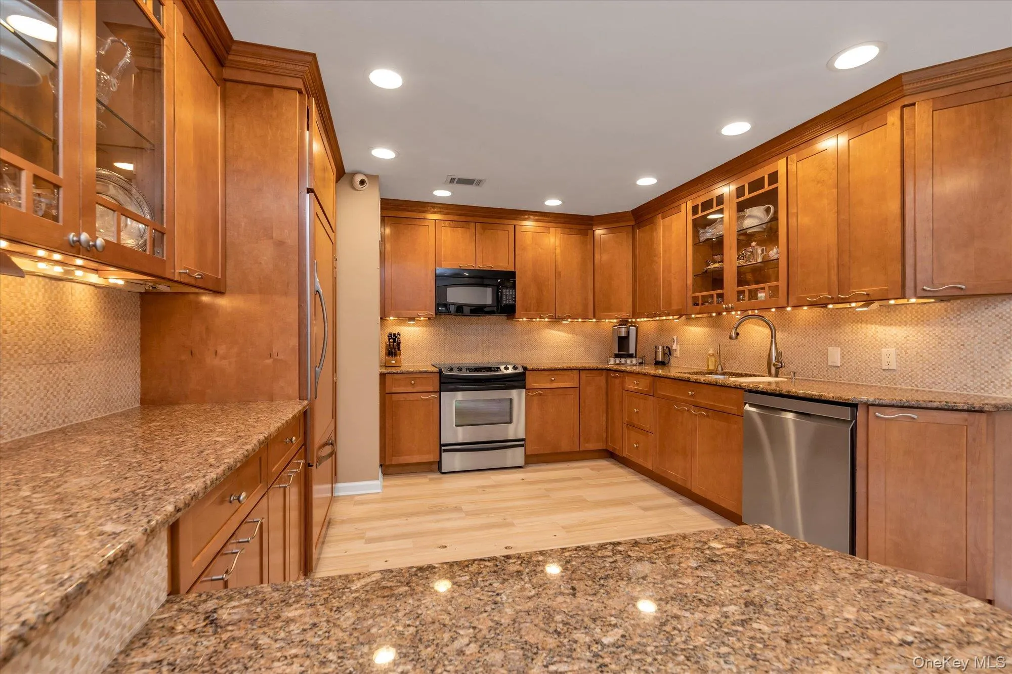 Kitchen featuring wood cabinetry, granite countertops, stainless steel appliances, mosaic tile backsplash, and recessed lighting Kitchen featuring wood cabinetry, granite countertops, stainless steel appliances, mosaic tile backsplash, and recessed lighting