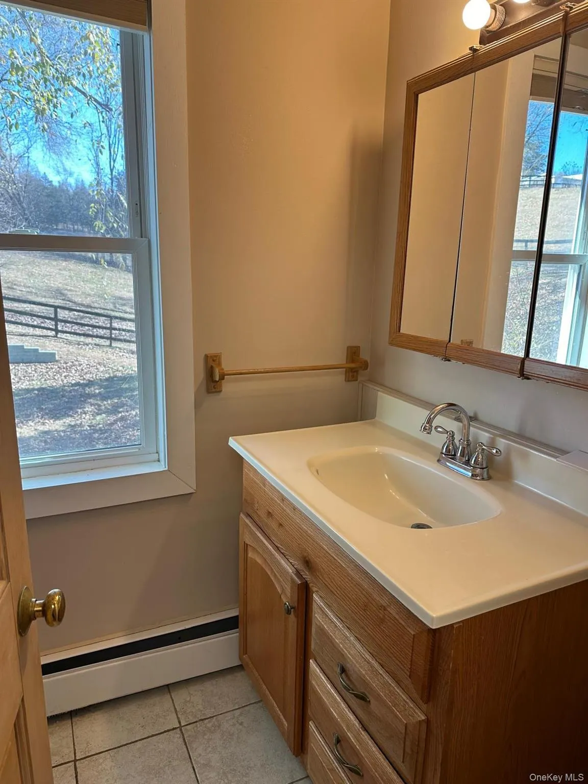 Bathroom with tile patterned flooring, vanity, and a baseboard radiator Bathroom with tile patterned flooring, vanity, and a baseboard radiator