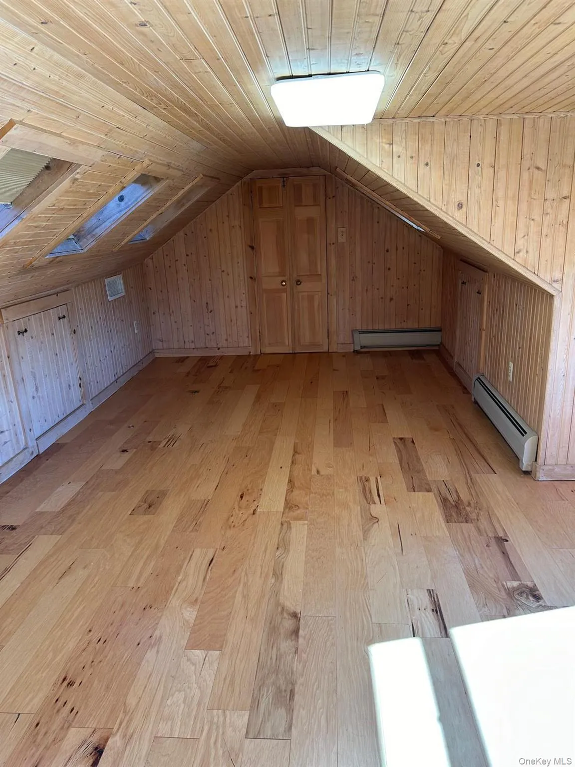 Bedroom with skylights and wood paneling and wood-style vinyl flooring Bedroom with skylights and wood paneling and wood-style vinyl flooring
