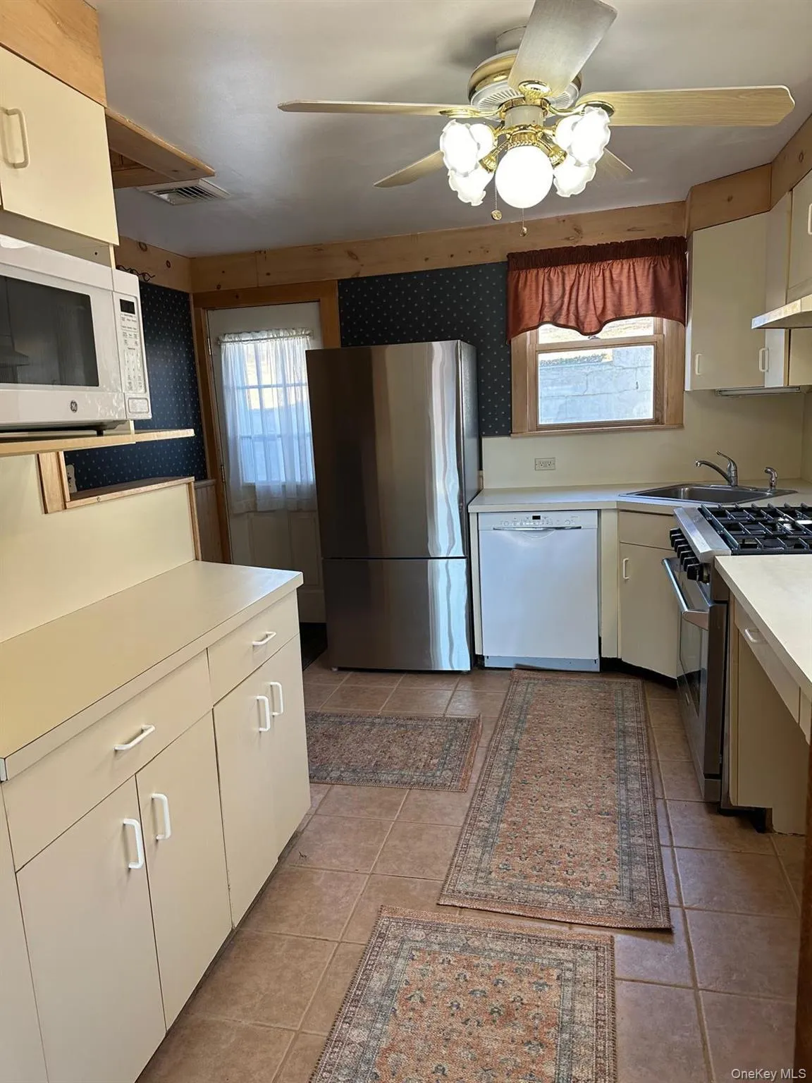 Tiled Kitchen featuring ceiling fan, sink, light tile patterned floors, and appliances with stainless steel finishes Tiled Kitchen featuring ceiling fan, sink, light tile patterned floors, and appliances with stainless steel finishes