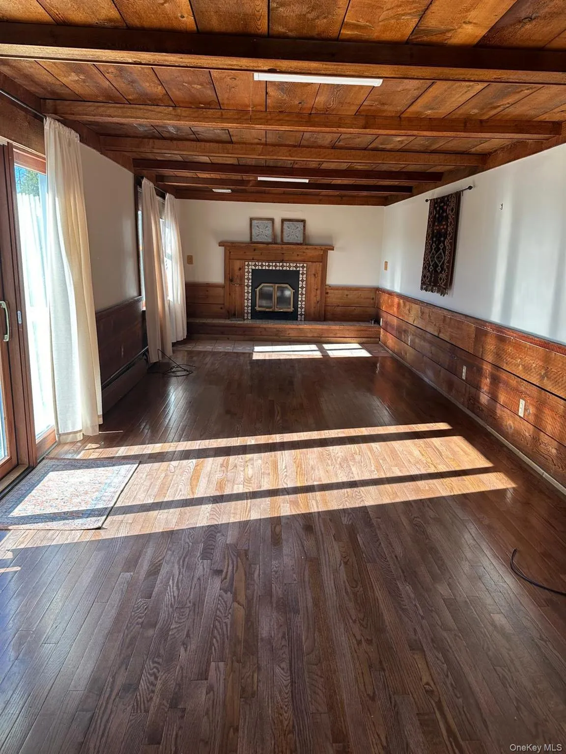Living room with wooden detailing throughout, fireplace, hardwood floors, and beamed wood ceiling Living room with wooden detailing throughout, fireplace, hardwood floors, and beamed wood ceiling