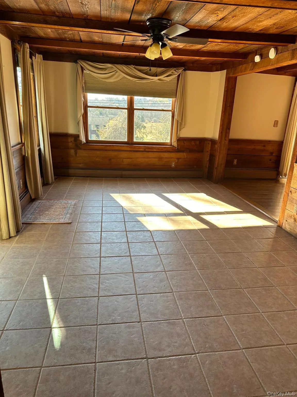 Tiled dining room featuring wood beam ceiling, ceiling fan, and wood detailing Tiled dining room featuring wood beam ceiling, ceiling fan, and wood detailing