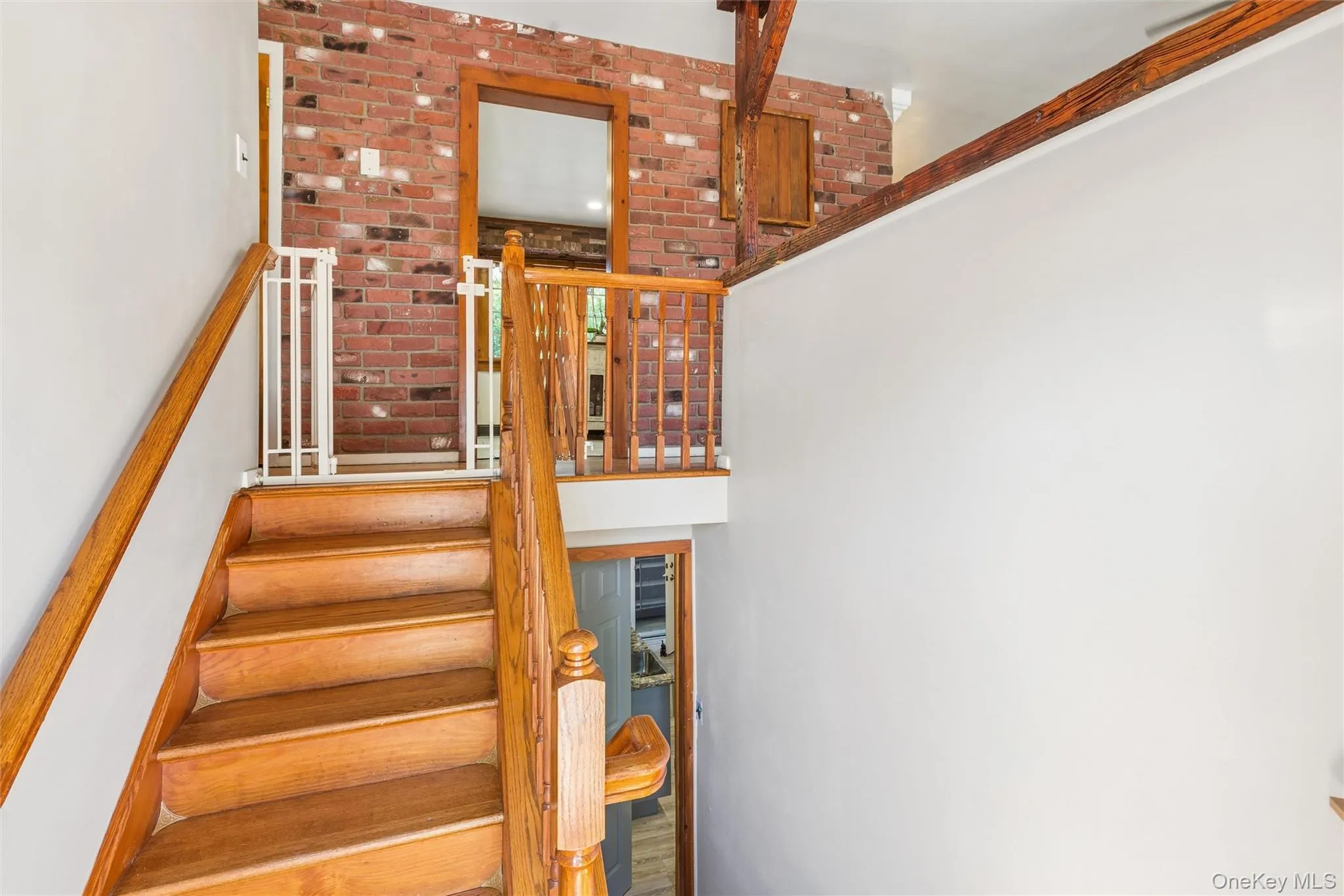 Beautiful hardwood staircase with natural wood railings, exposed brick wall, and overhead wood beams Beautiful hardwood staircase with natural wood railings, exposed brick wall, and overhead wood beams