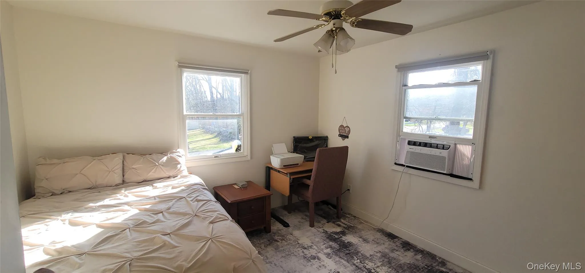 Bedroom featuring cooling unit, multiple windows, wood finished floors, and a ceiling fan Bedroom featuring cooling unit, multiple windows, wood finished floors, and a ceiling fan
