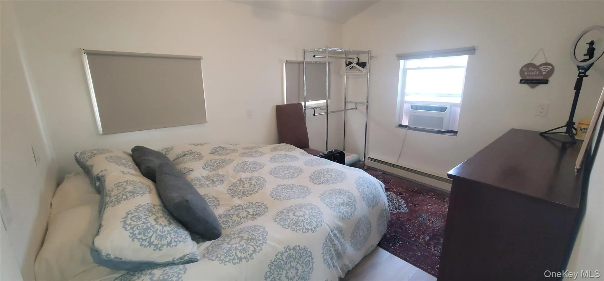 Bedroom with cooling unit, baseboard heating, and wood finished floors Bedroom with cooling unit, baseboard heating, and wood finished floors