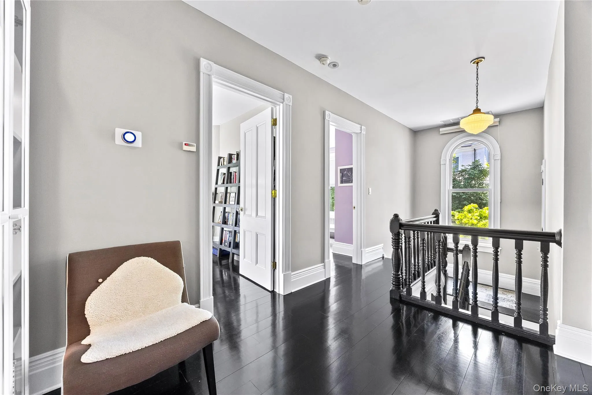 Upper landing featuring dark wood-finish flooring, white trim, and a black balustrade Upper landing featuring dark wood-finish flooring, white trim, and a black balustrade