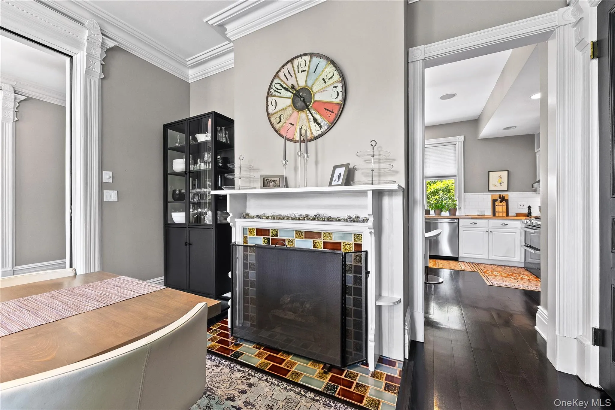 Decorative fireplace in formal dining area with an ornate white mantel and colorful tile surround, complemented by dark wood-finish flooring. Decorative fireplace in formal dining area with an ornate white mantel and colorful tile surround, complemented by dark wood-finish flooring.