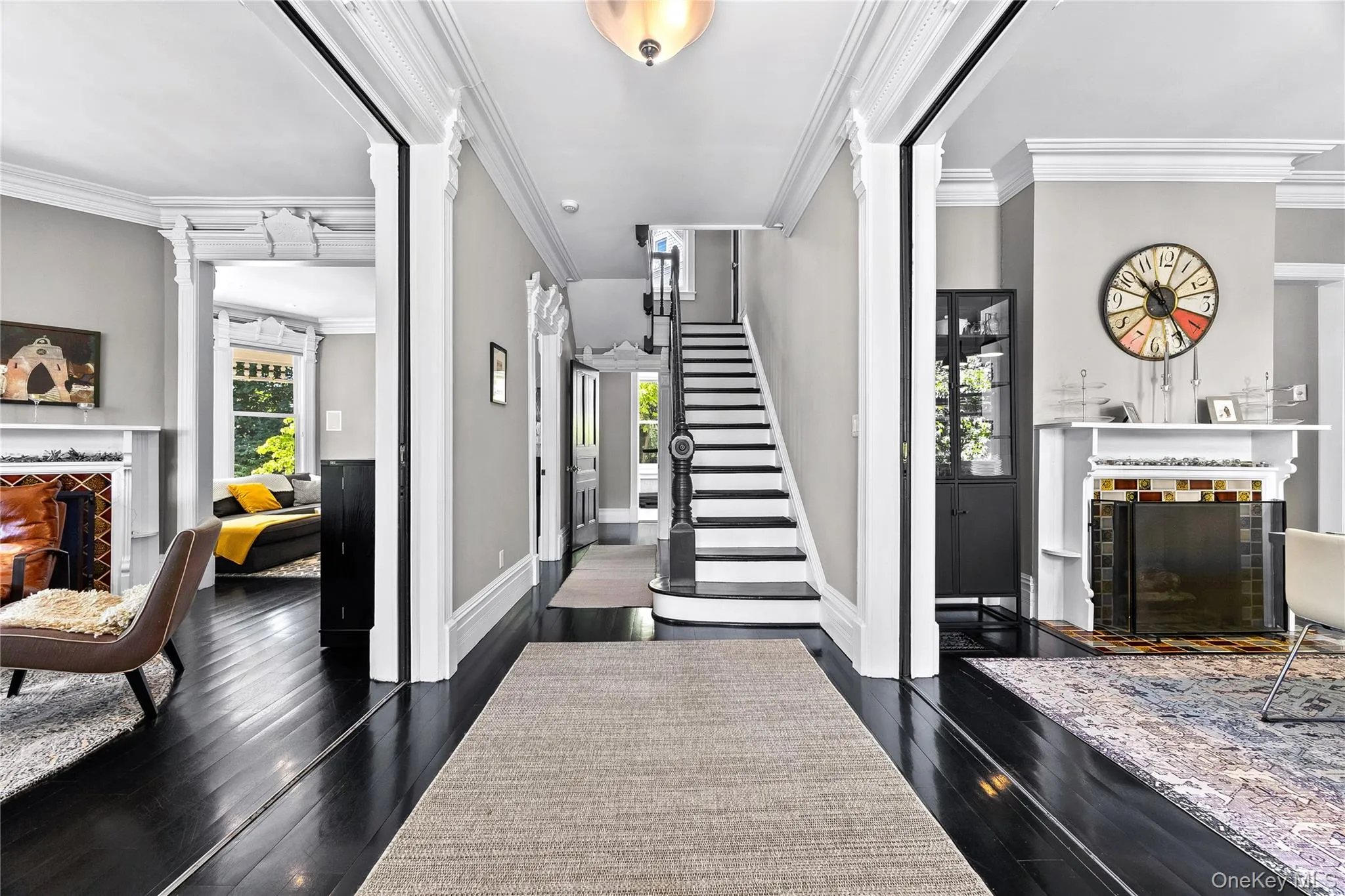 Formal entryway with dark wood-finish flooring, a grand staircase, and detailed crown molding Formal entryway with dark wood-finish flooring, a grand staircase, and detailed crown molding
