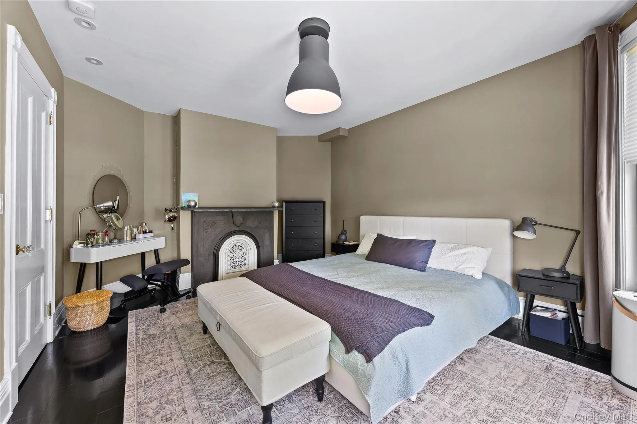 Bedroom featuring dark wood-finish flooring, a decorative fireplace with an ornate insert, recessed lighting, and a contemporary ceiling fixture Bedroom featuring dark wood-finish flooring, a decorative fireplace with an ornate insert, recessed lighting, and a contemporary ceiling fixture