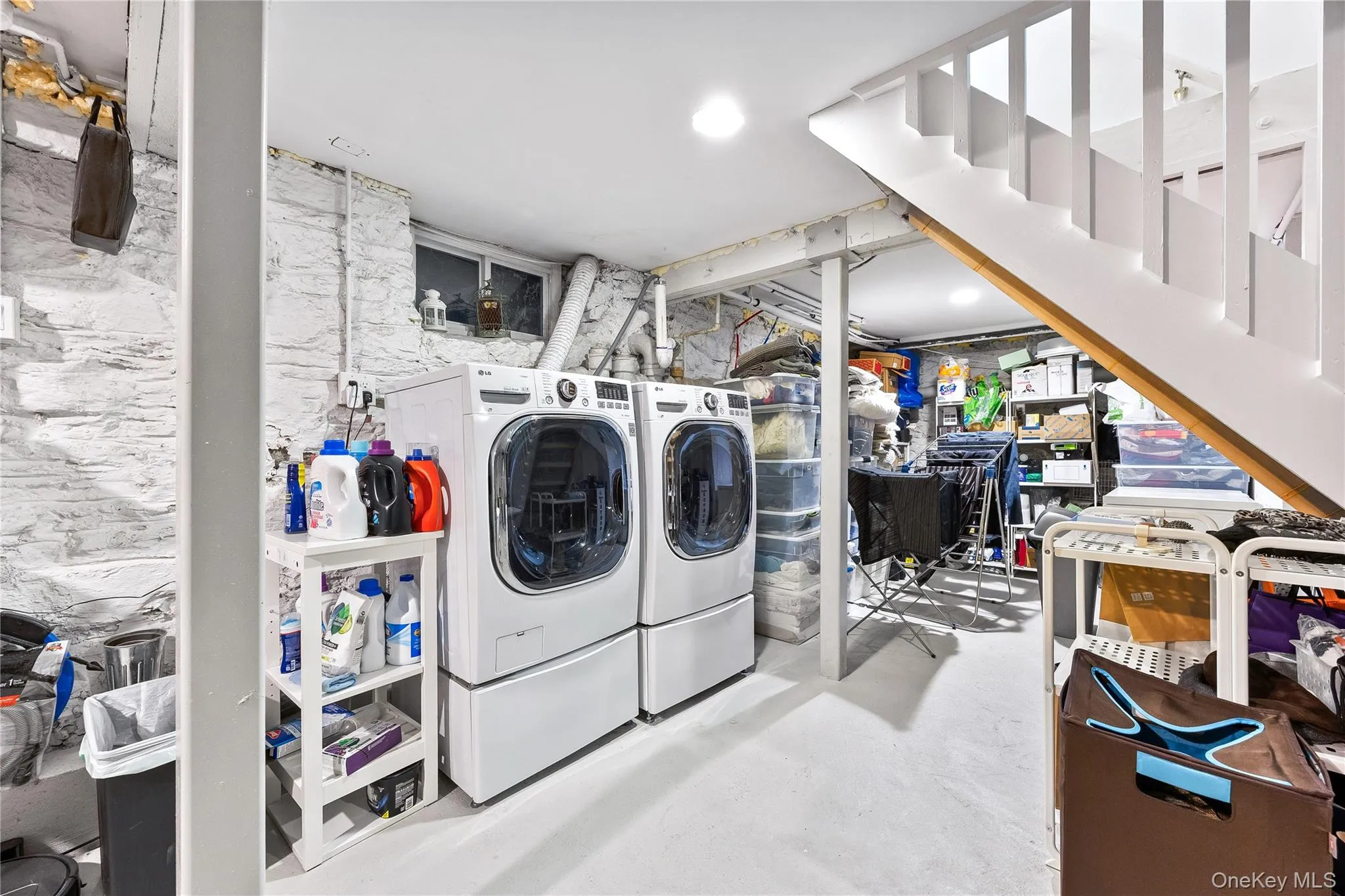 Laundry area with white painted stone walls, recessed lighting, and a white open-tread staircase Laundry area with white painted stone walls, recessed lighting, and a white open-tread staircase