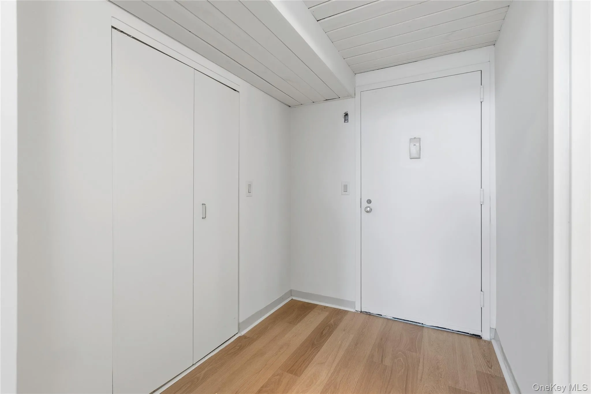 Hallway with wood-finish flooring and white walls Hallway with wood-finish flooring and white walls