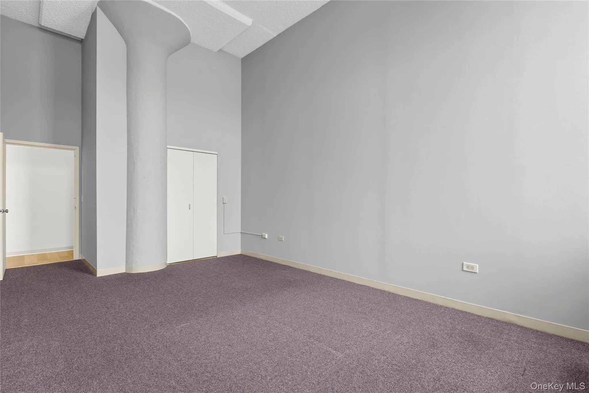 Bedroom with two tall windows, grey walls, and purple carpet flooring Bedroom with two tall windows, grey walls, and purple carpet flooring