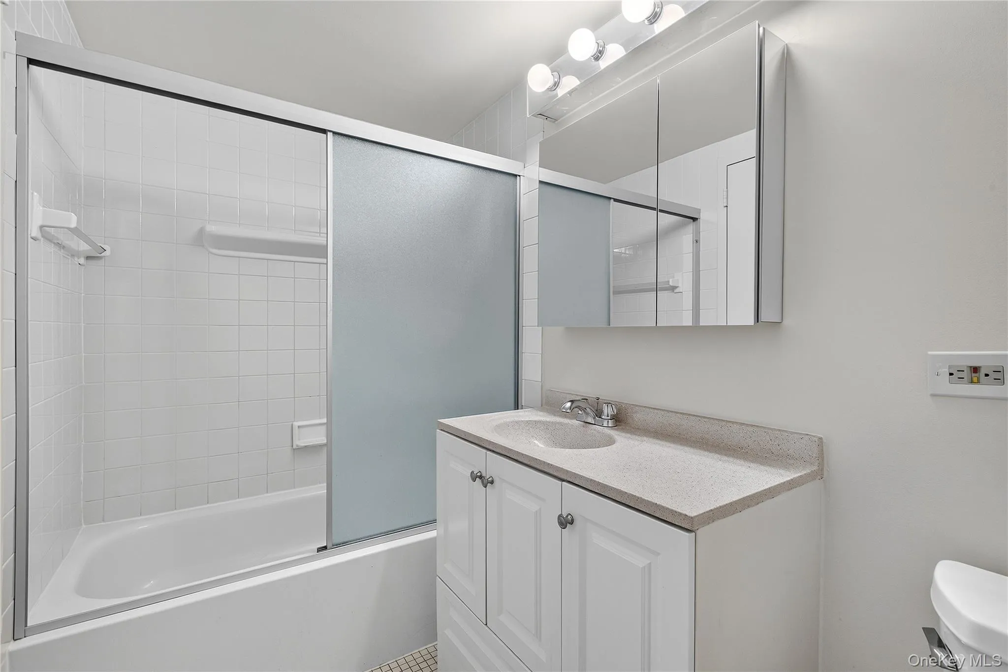 Bathroom featuring a white vanity with a light-toned countertop, an integrated sink, and chrome fixtures Bathroom featuring a white vanity with a light-toned countertop, an integrated sink, and chrome fixtures