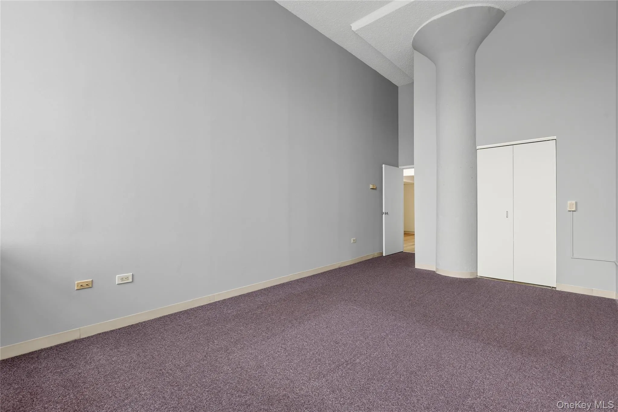 Bedroom with two tall windows, grey walls, and purple carpet flooring Bedroom with two tall windows, grey walls, and purple carpet flooring
