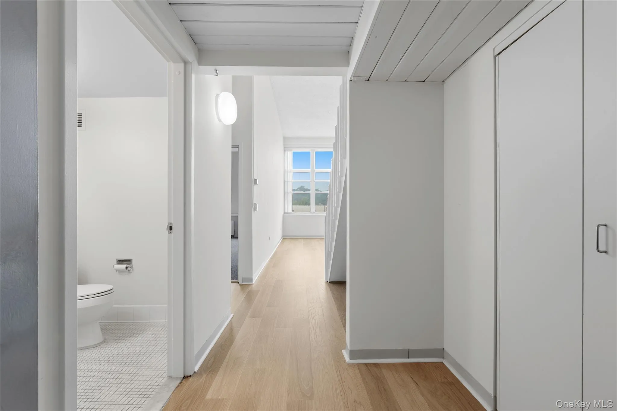 Hallway with wood-finish flooring and white walls Hallway with wood-finish flooring and white walls