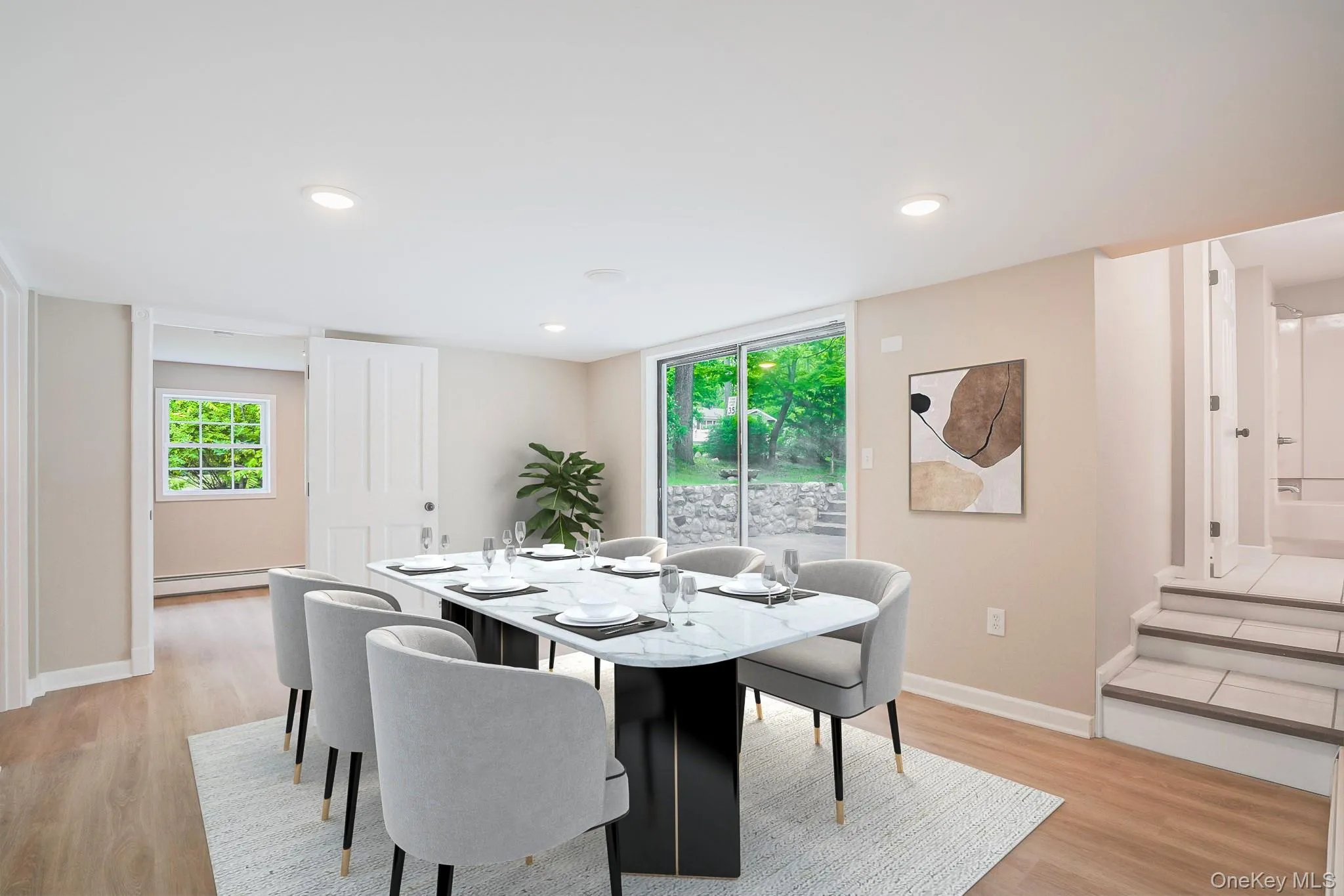 Spacious room featuring light wood-finish flooring, recessed lighting, and a sliding glass door providing access to the outdoors Spacious room featuring light wood-finish flooring, recessed lighting, and a sliding glass door providing access to the outdoors
