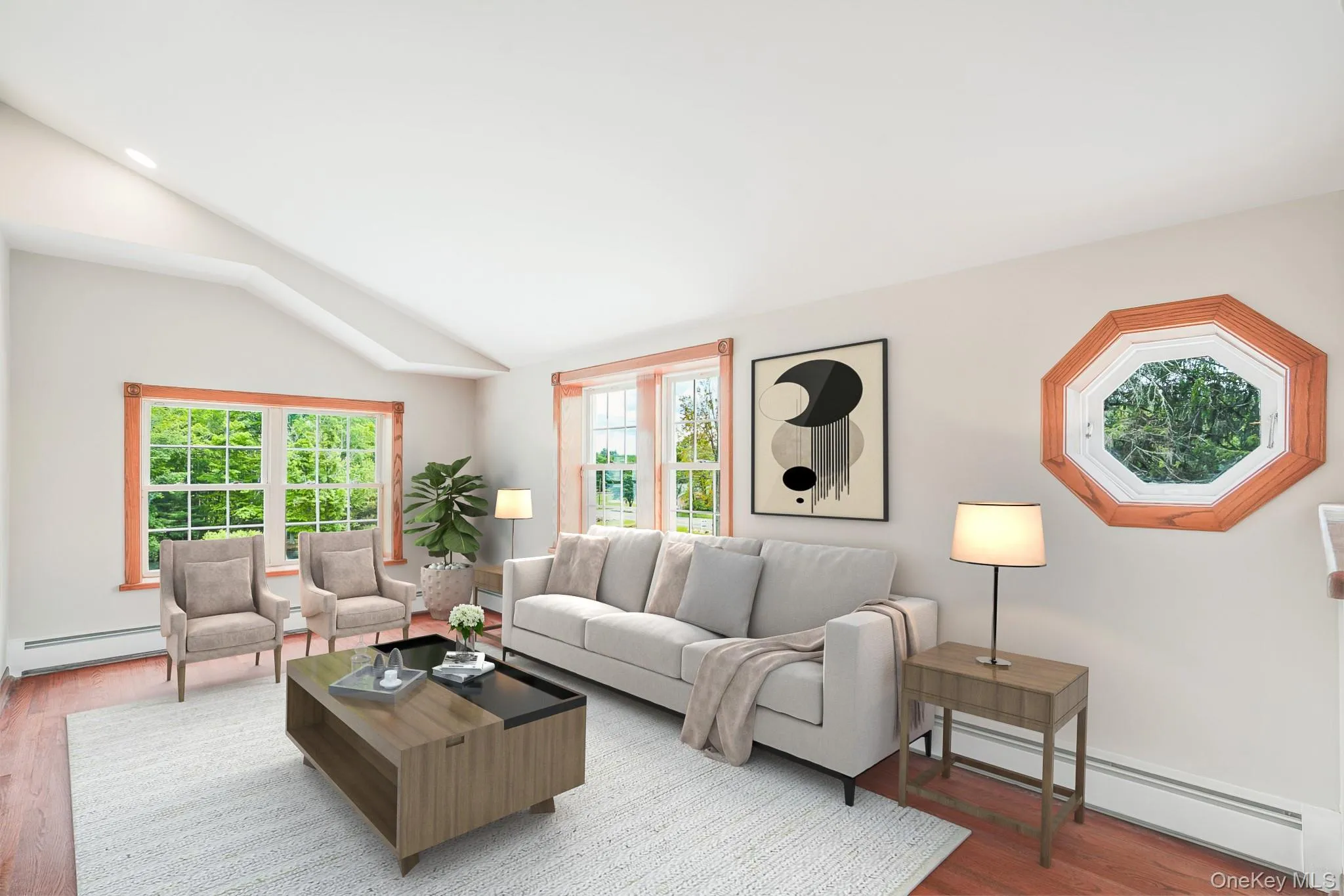 Spacious living area featuring a vaulted ceiling, wood-finish flooring, and multiple windows providing natural light Spacious living area featuring a vaulted ceiling, wood-finish flooring, and multiple windows providing natural light