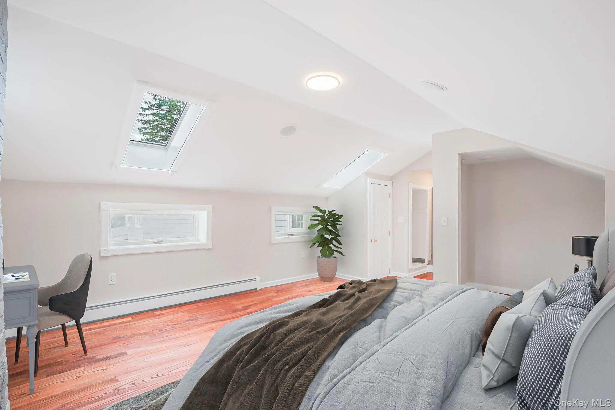 Slanted ceiling room featuring two skylights, two horizontal windows, wood-finish flooring, and recessed lighting Slanted ceiling room featuring two skylights, two horizontal windows, wood-finish flooring, and recessed lighting