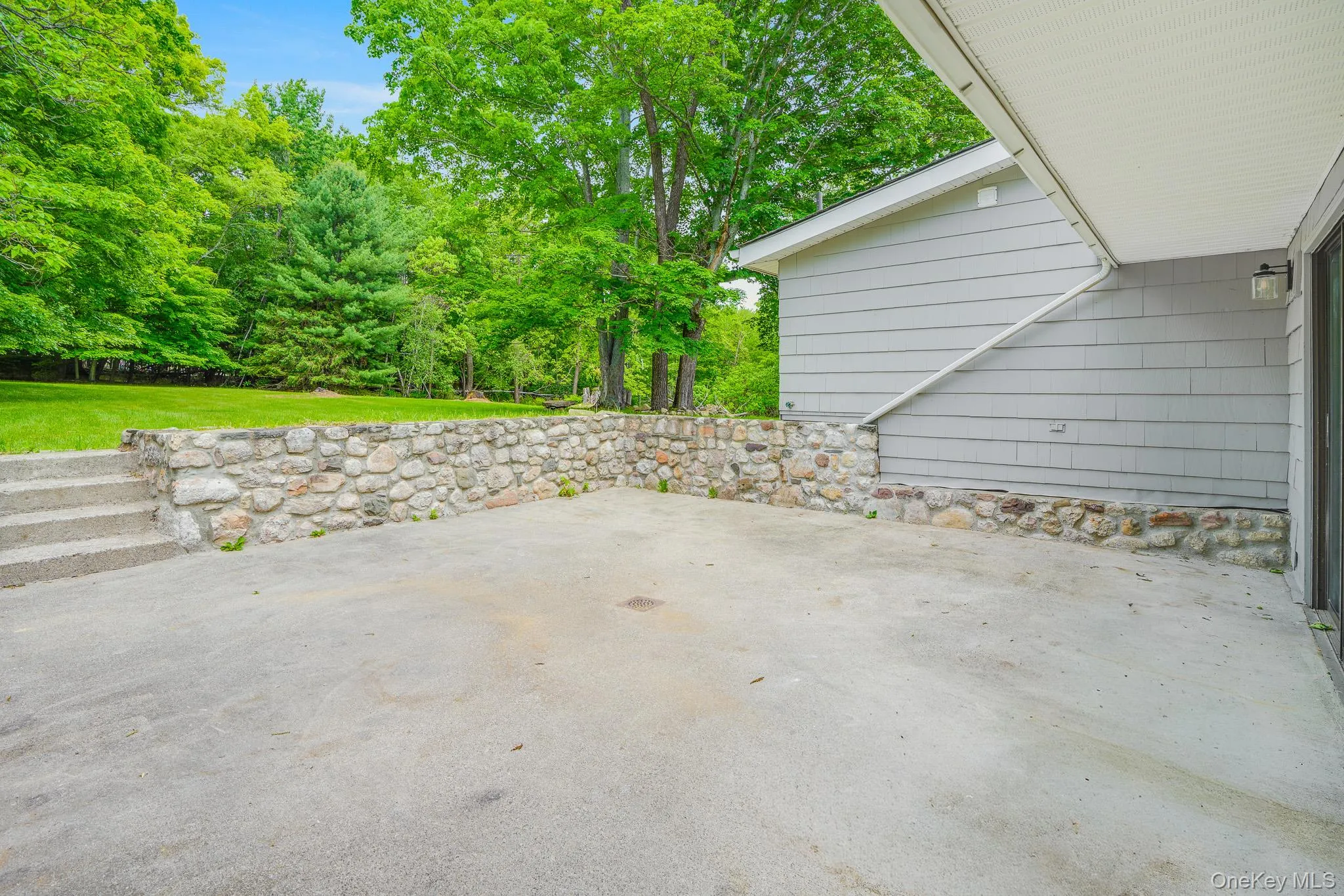 Concrete patio area bordered by a stone retaining wall and concrete steps Concrete patio area bordered by a stone retaining wall and concrete steps