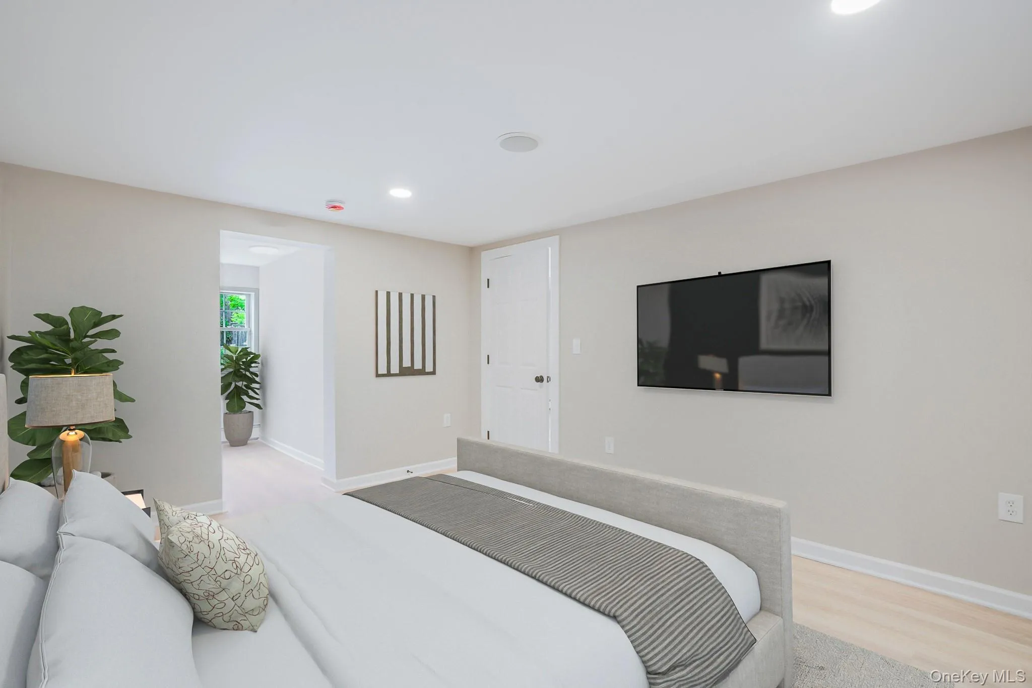 Bedroom featuring light-toned flooring, recessed lighting, and a white paneled door Bedroom featuring light-toned flooring, recessed lighting, and a white paneled door