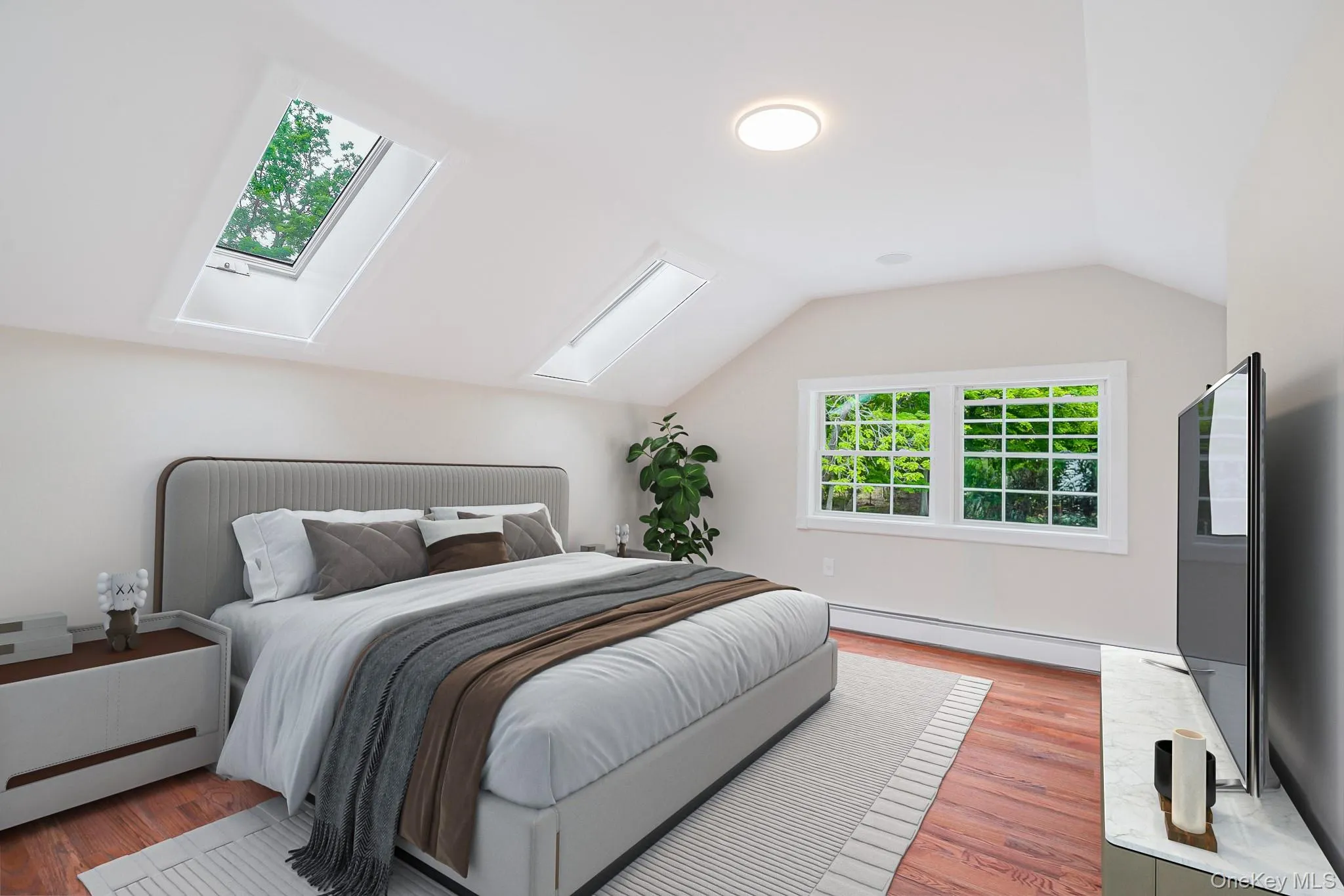 Bedroom featuring a vaulted ceiling, two skylights, and wood-finish flooring Bedroom featuring a vaulted ceiling, two skylights, and wood-finish flooring