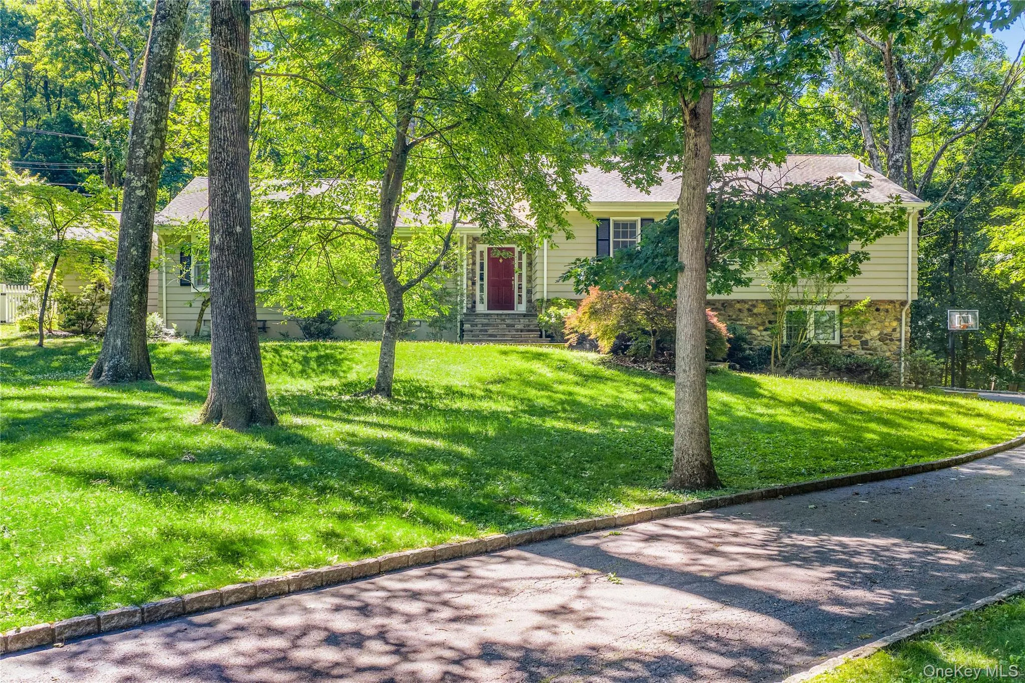 The stone and clapboard exterior is shaded by towering trees and lush lawns The stone and clapboard exterior is shaded by towering trees and lush lawns