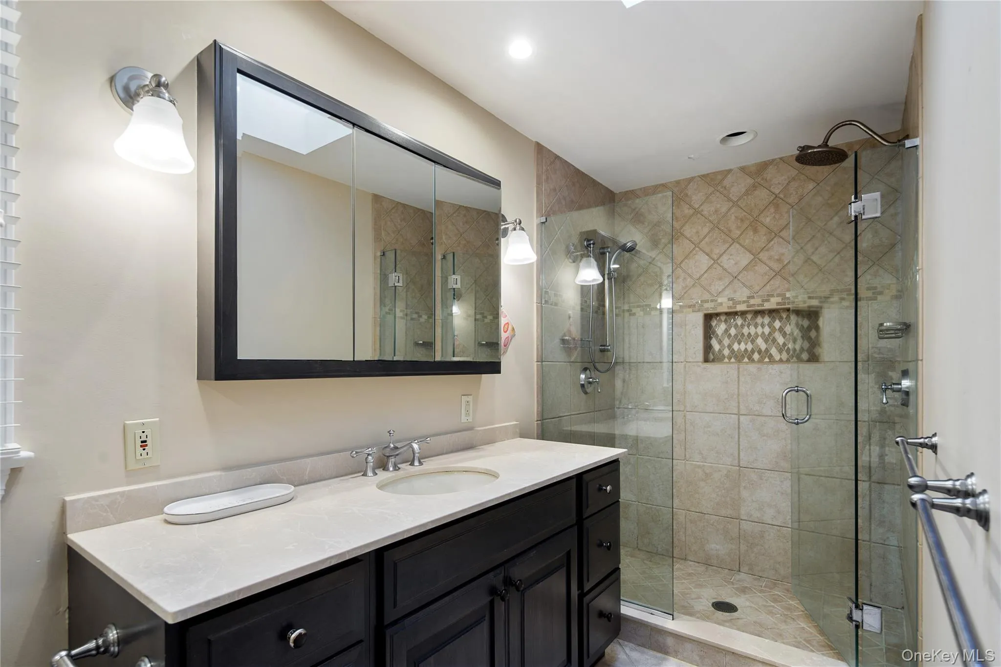 The primary en-suite bath offers a large shower with frameless glass enclosure, rain head and adjustable shower heads, built-in product niche, large storage vanity with undermount sink, triple medicine cabinet with beveled edge mirrors, wall sconces, polished chrome plumbing fixtures and a separate jetted tub The primary en-suite bath offers a large shower with frameless glass enclosure, rain head and adjustable shower heads, built-in product niche, large storage vanity with undermount sink, triple medicine cabinet with beveled edge mirrors, wall sconces, polished chrome plumbing fixtures and a separate jetted tub