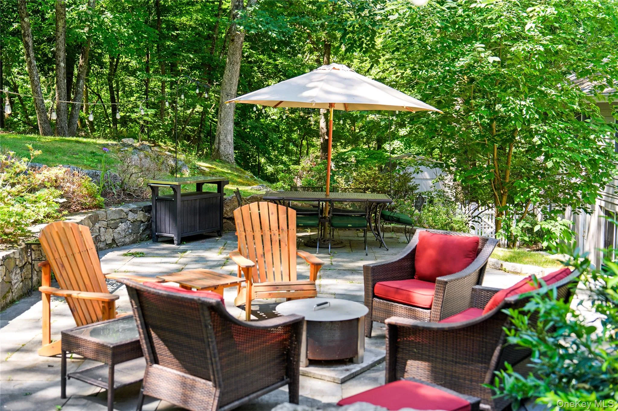 Stone knee walls create an outdoor enclave, an intimate spot for outdoor relaxation amidst an expansive backyard rimmed by towering old growth trees Stone knee walls create an outdoor enclave, an intimate spot for outdoor relaxation amidst an expansive backyard rimmed by towering old growth trees