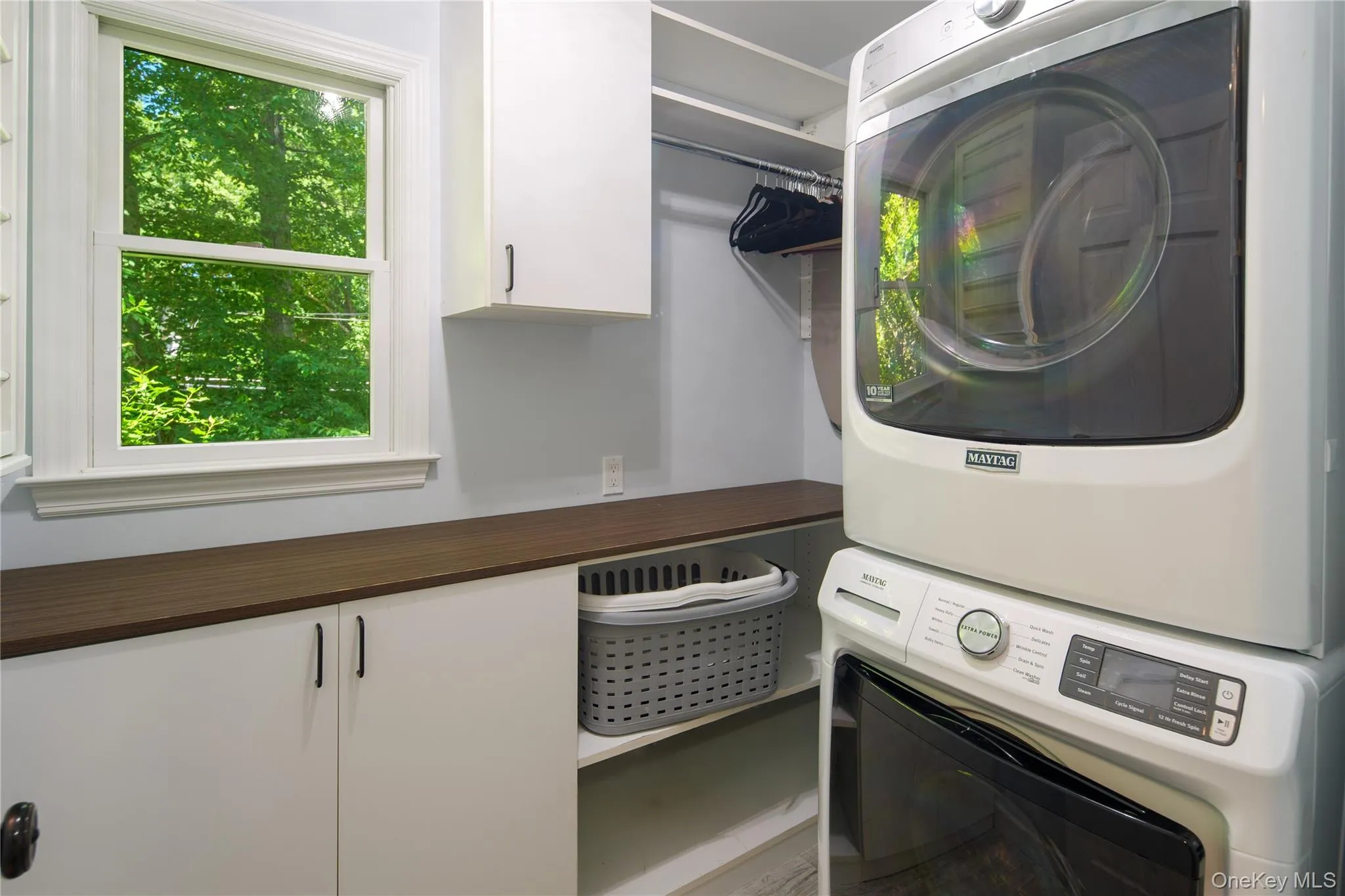 Main floor windowed laundry room with folding counter, storage shelving and cabinetry, built-in drying rack, tile floor. Main floor windowed laundry room with folding counter, storage shelving and cabinetry, built-in drying rack, tile floor.