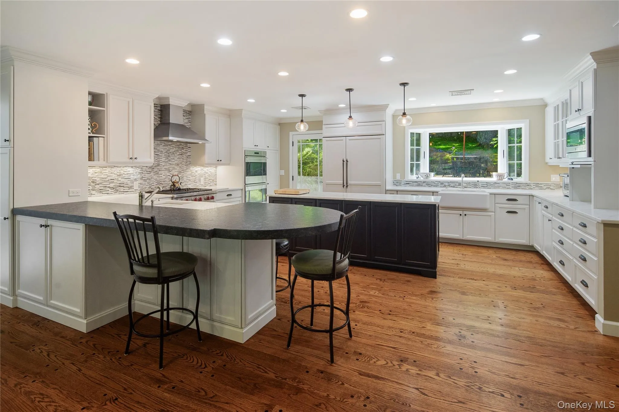 The renovated kitchen features both a seating peninsula and a center island, honed granite and Carrera marble counters, sparkling white soft close cabinetry with interior pullouts, a Shaw farmhouse sink and addt'l prep sink, a large Subzero and Bosch dishwasher with integral door panels, stainless steel Wolf convection double wall ovens and Wolf 6 burner gas cooktop, an appliance garage, pendant and recessed lighting, a large bay window overlooking the back patios and yard, glazed display cabinets, cookbook shelves, a built-in microwave, wide board pegged oak floors, a large walk-in pantry, and a door out to the patio. The renovated kitchen features both a seating peninsula and a center island, honed granite and Carrera marble counters, sparkling white soft close cabinetry with interior pullouts, a Shaw farmhouse sink and addt'l prep sink, a large Subzero and Bosch dishwasher with integral door panels, stainless steel Wolf convection double wall ovens and Wolf 6 burner gas cooktop, an appliance garage, pendant and recessed lighting, a large bay window overlooking the back patios and yard, glazed display cabinets, cookbook shelves, a built-in microwave, wide board pegged oak floors, a large walk-in pantry, and a door out to the patio.
